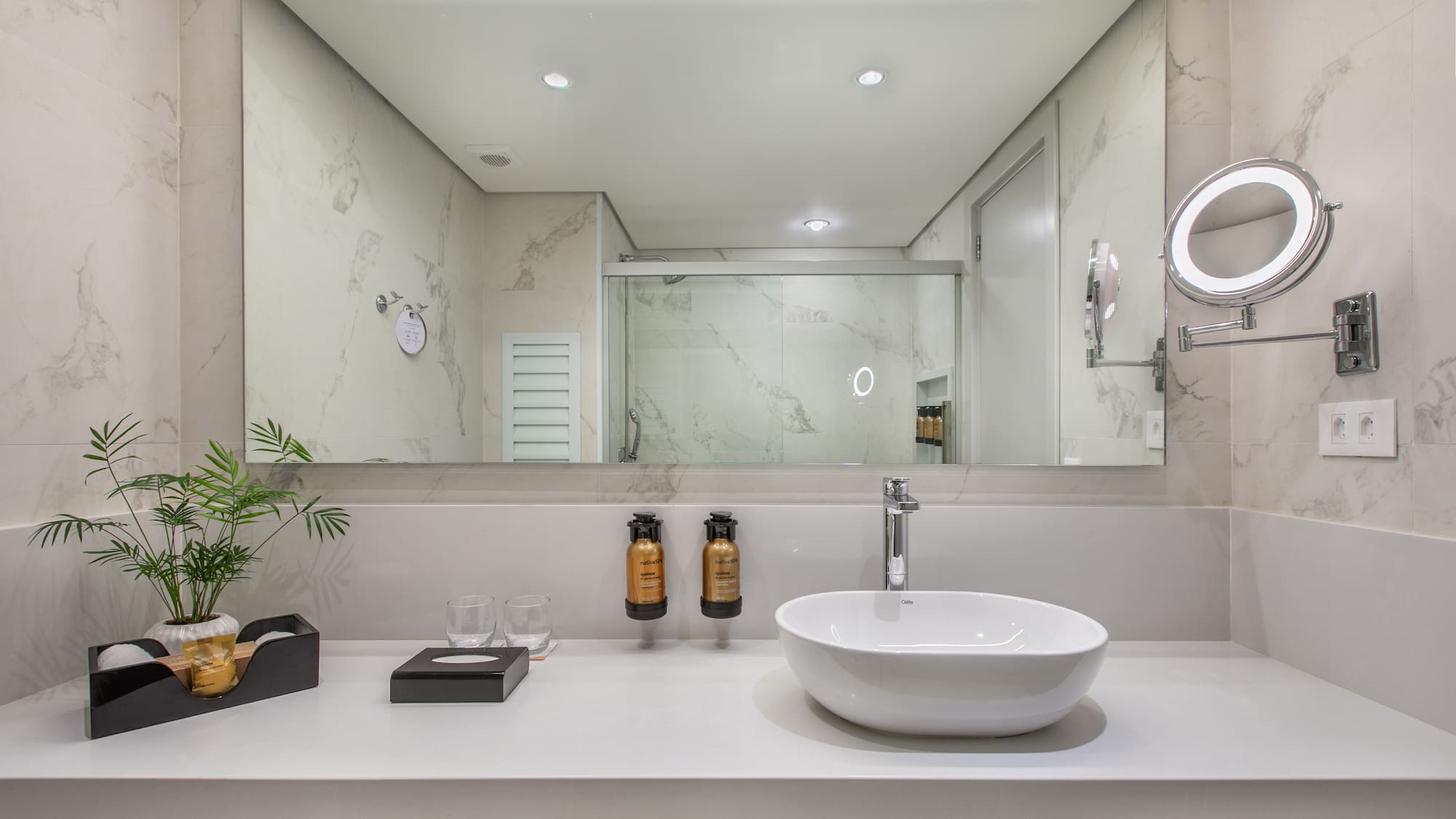 Modern hotel bathroom with white vanity, vessel sink, and large mirror.