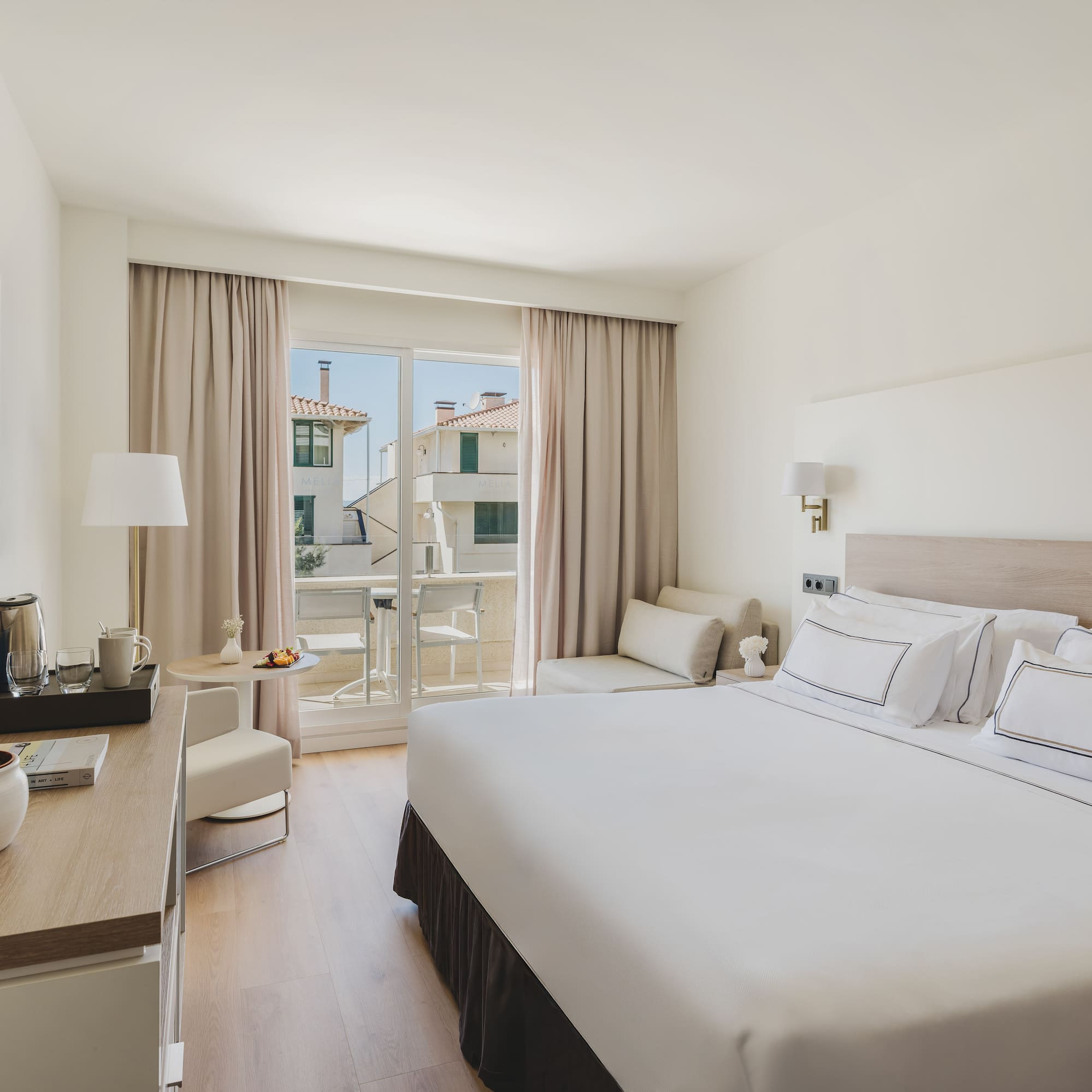 Moderna habitación de hotel con cama doble, balcón y vistas urbanas.