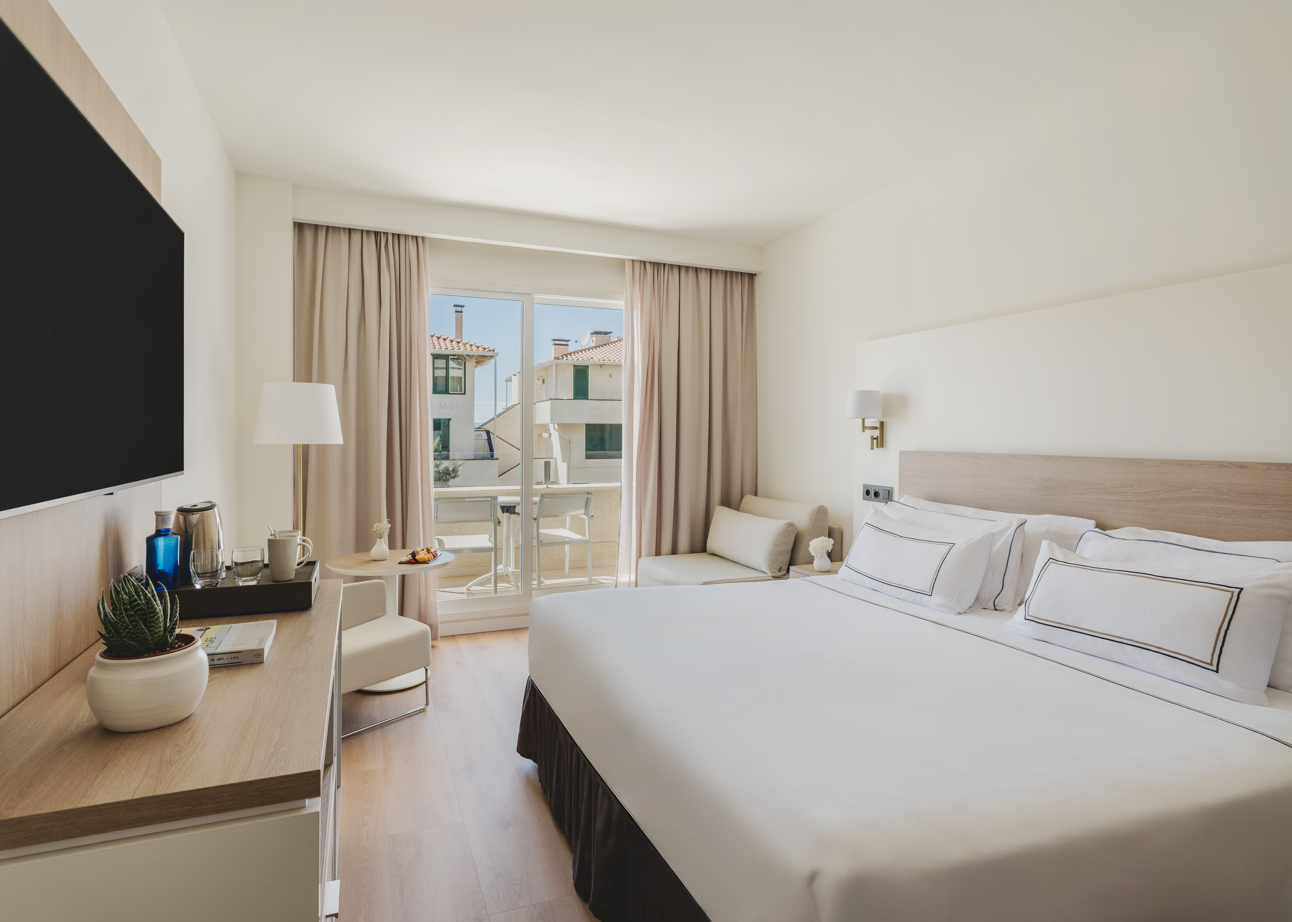 Moderna habitación de hotel con cama doble, balcón y vistas urbanas.