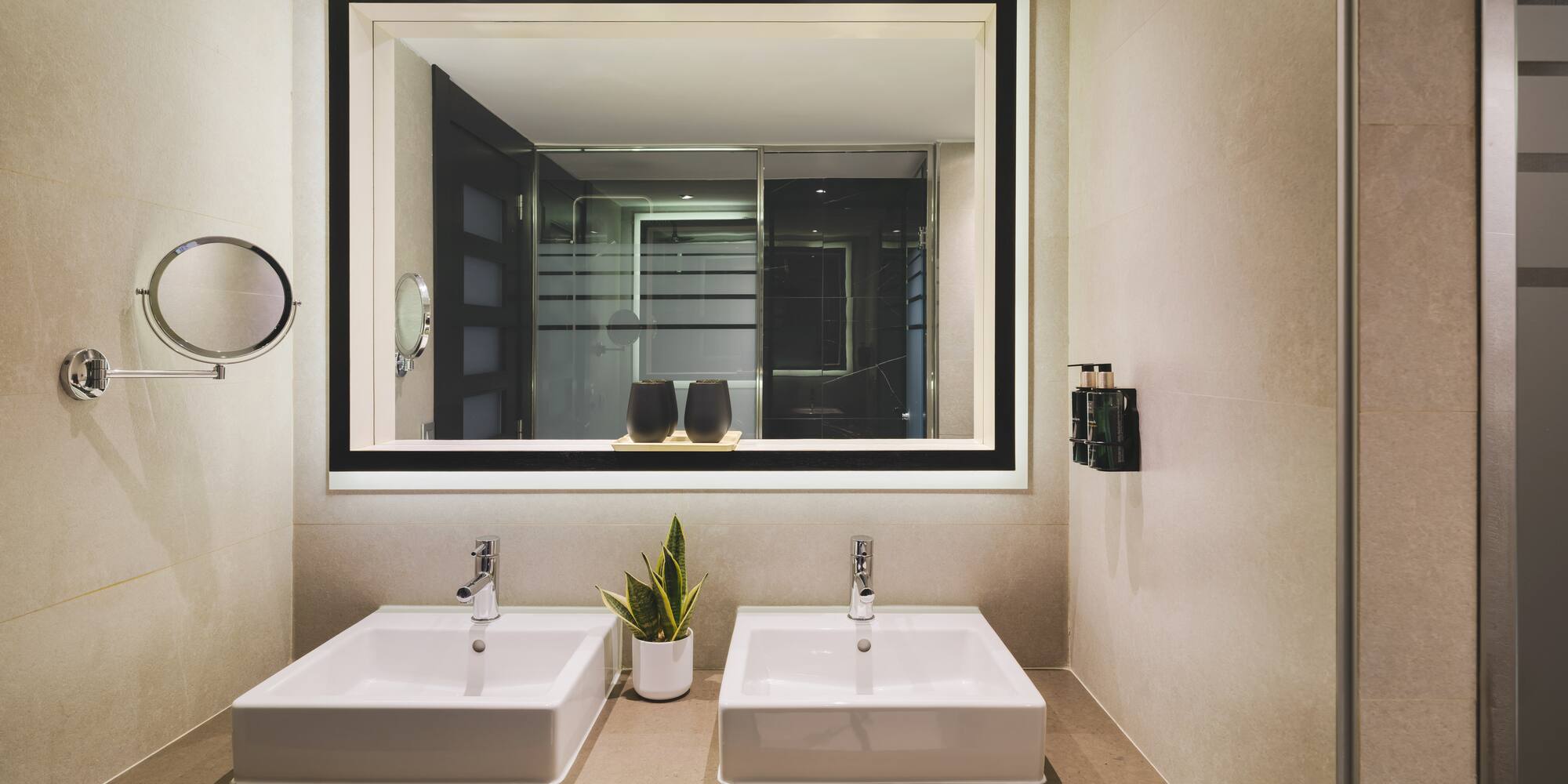 Baño de hotel moderno con doble lavabo y espejo iluminado.
