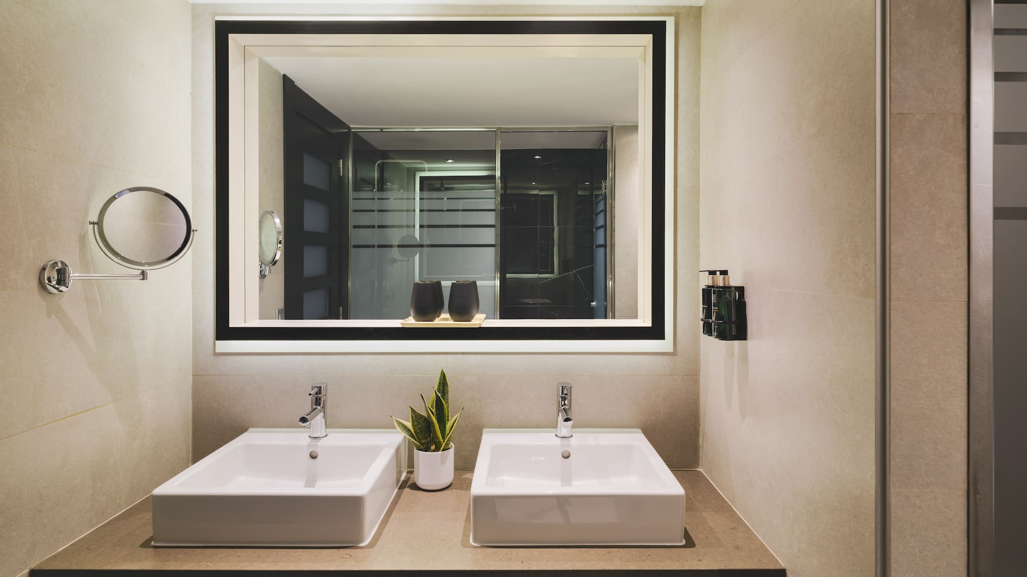 Baño de hotel moderno con doble lavabo y espejo iluminado.