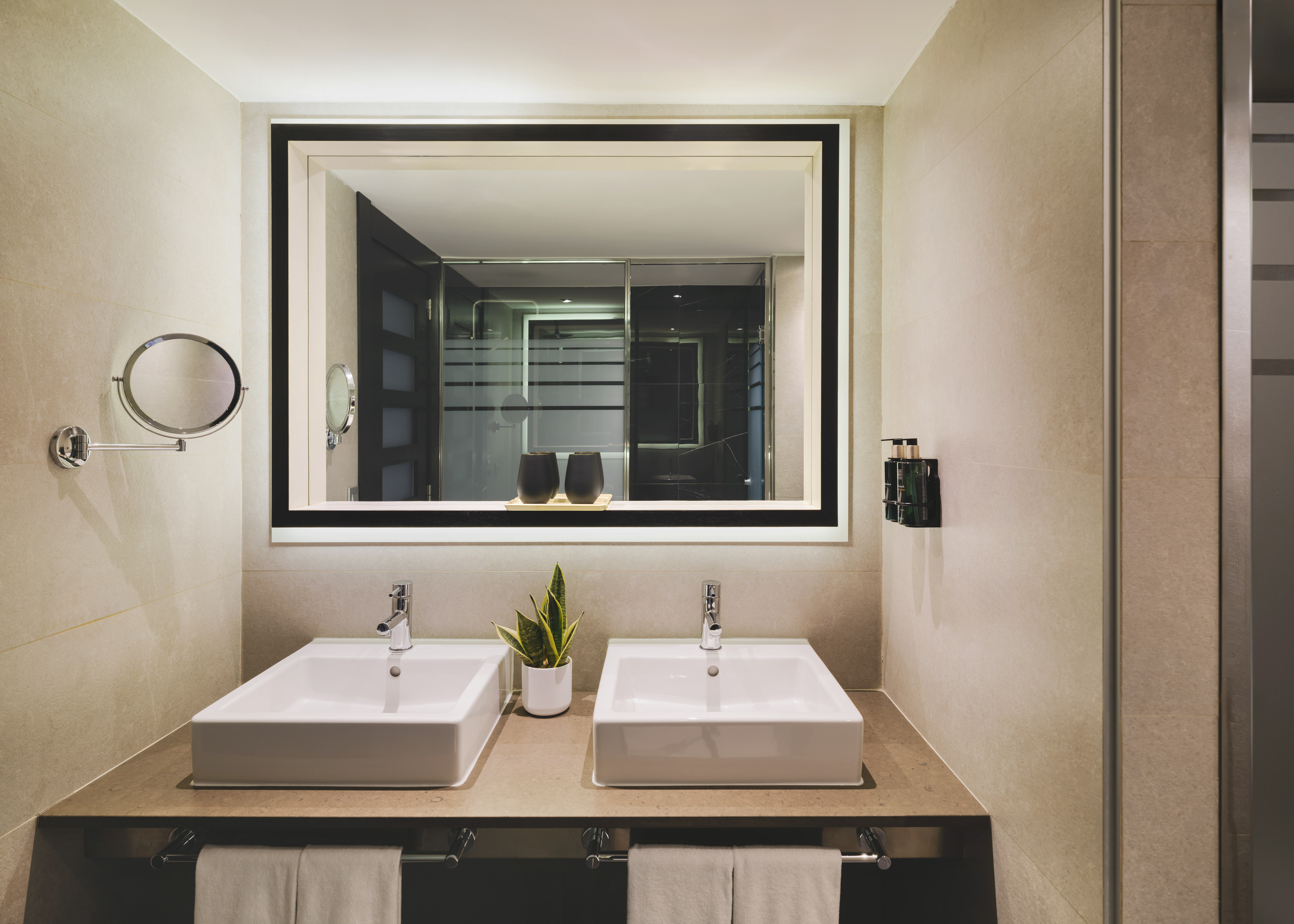 Baño de hotel moderno con doble lavabo y espejo iluminado.