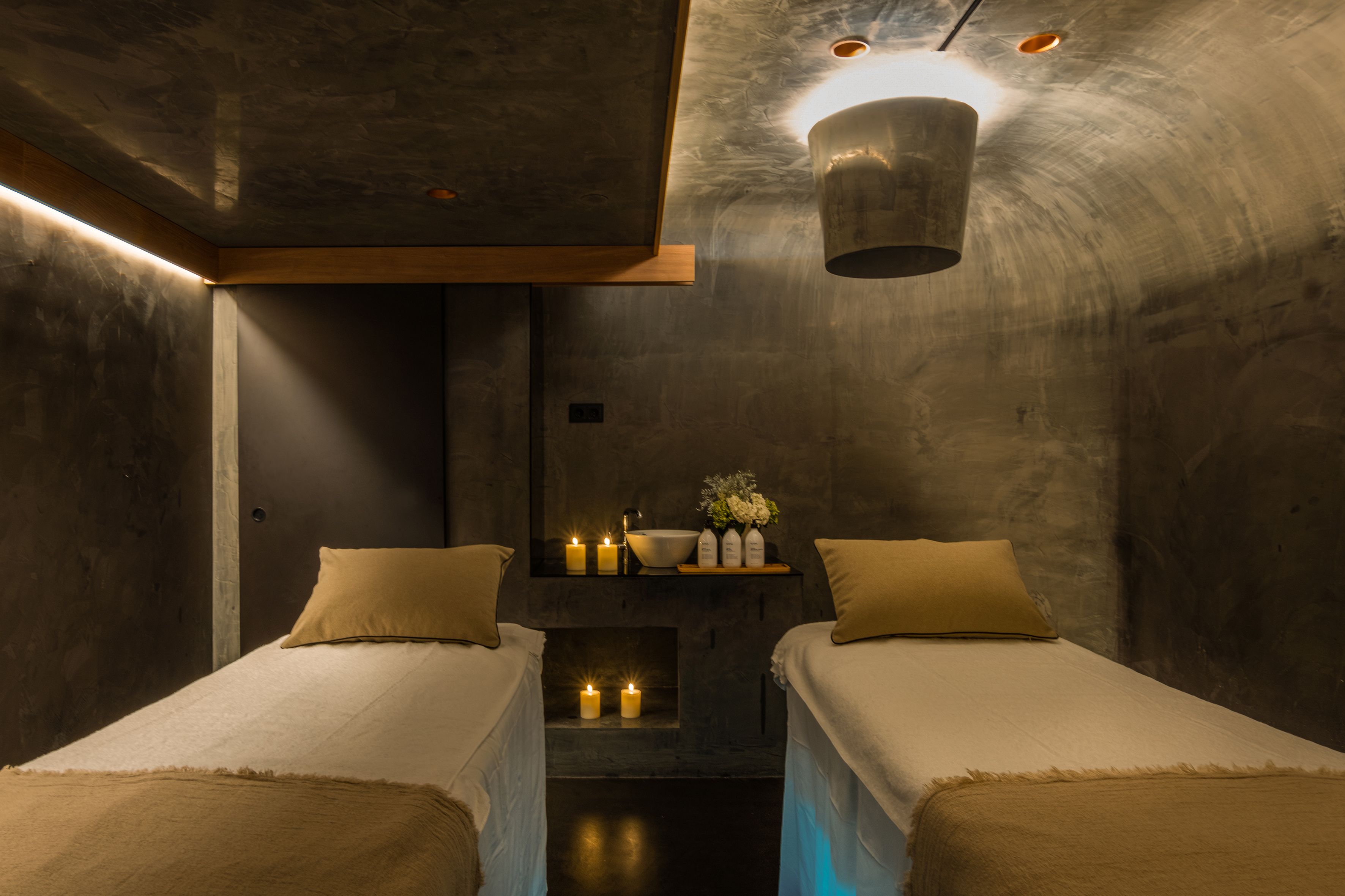 Couples spa room with two massage tables, candles, and warm lighting.