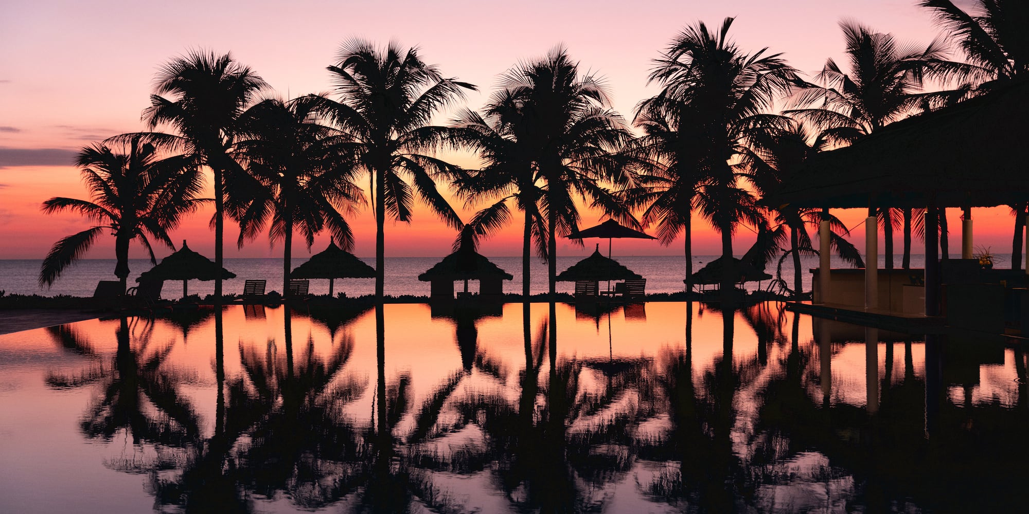 a pool with palm trees and a sunset