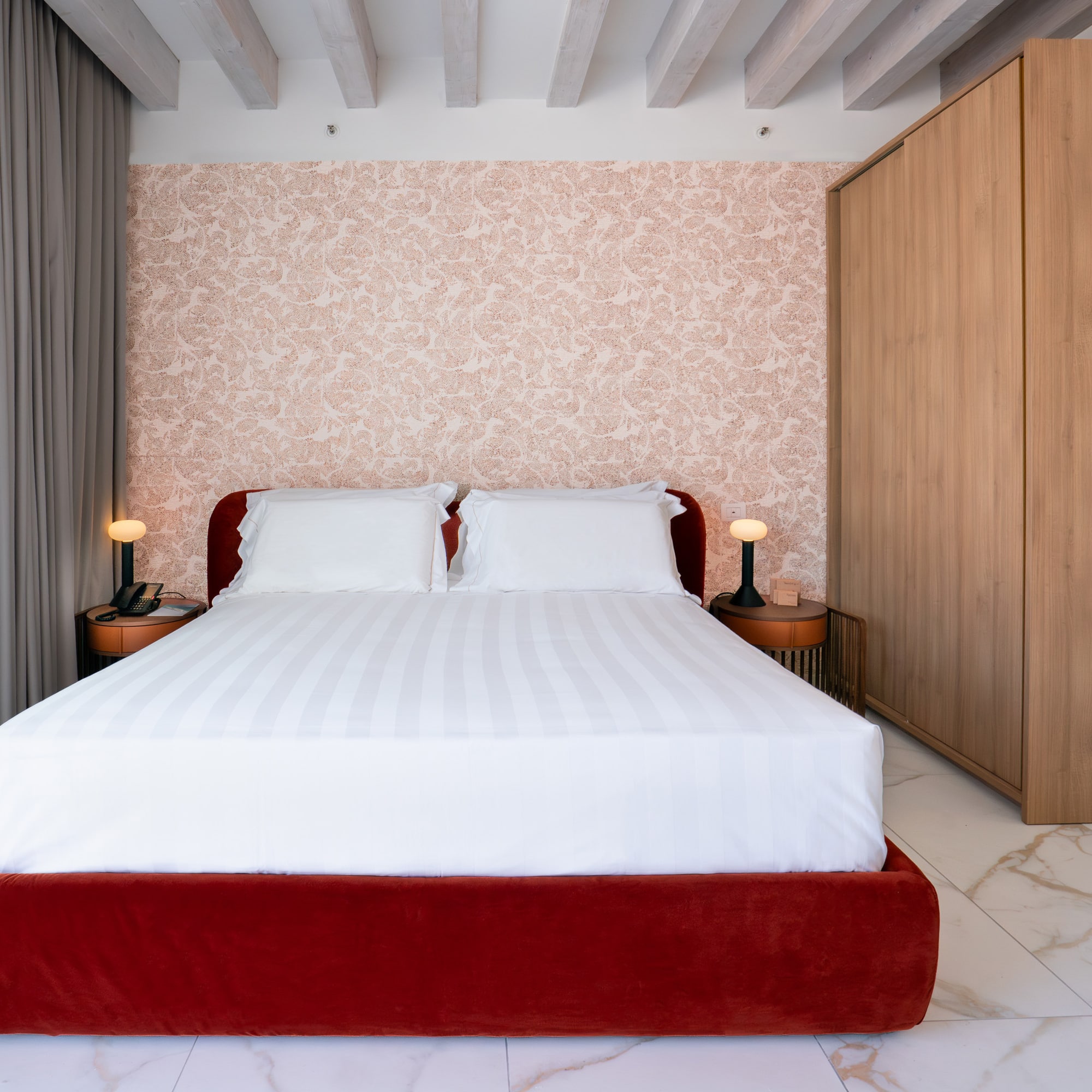 Modern bedroom with red velvet bed, patterned wallpaper, wood wardrobe, marble.
