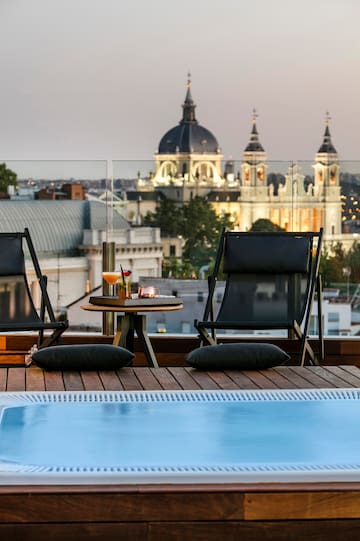 a pool with a table and chairs on a rooftop with a city in the background