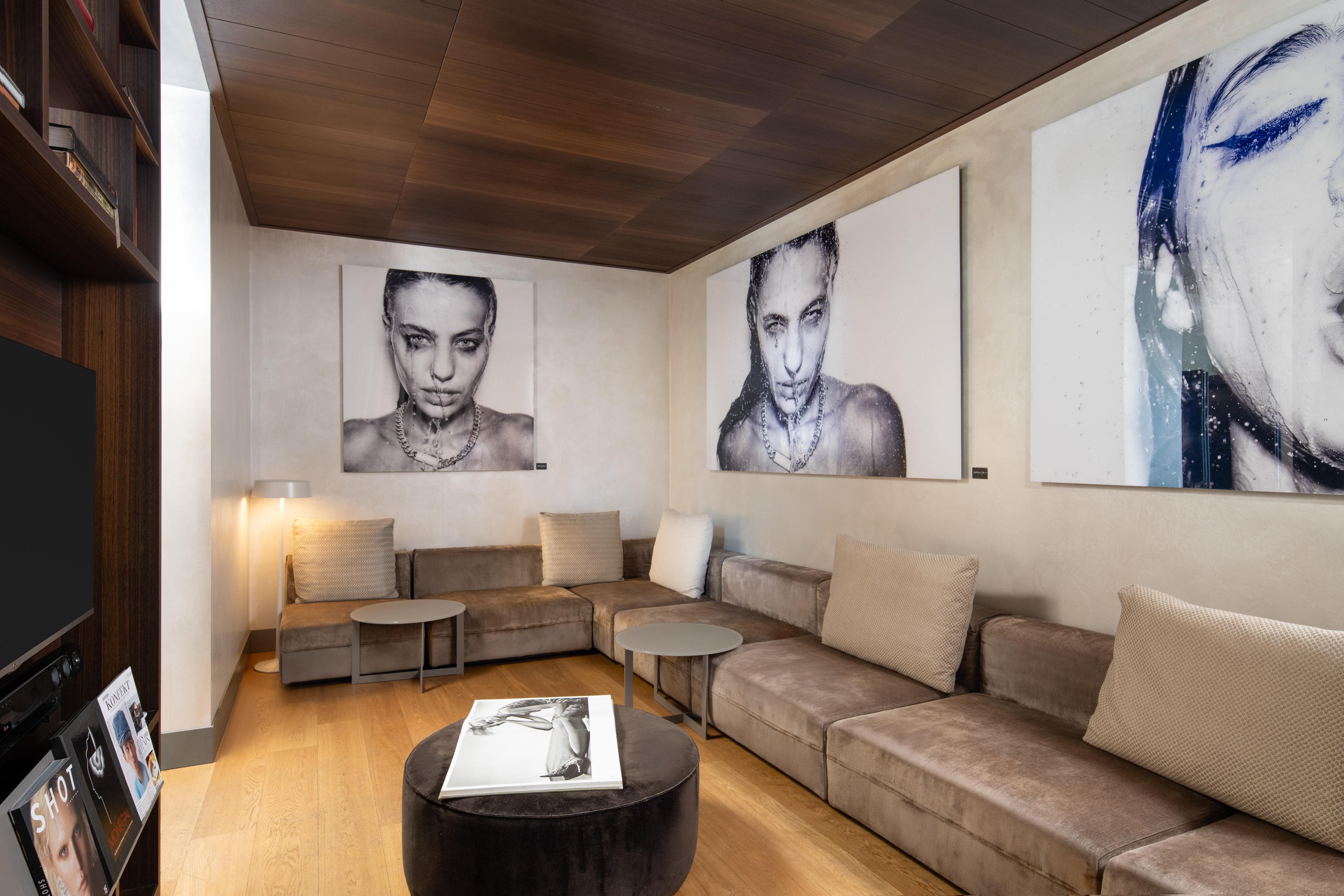 Modern lounge with brown velvet sofa, wood ceiling, large contemporary art.
