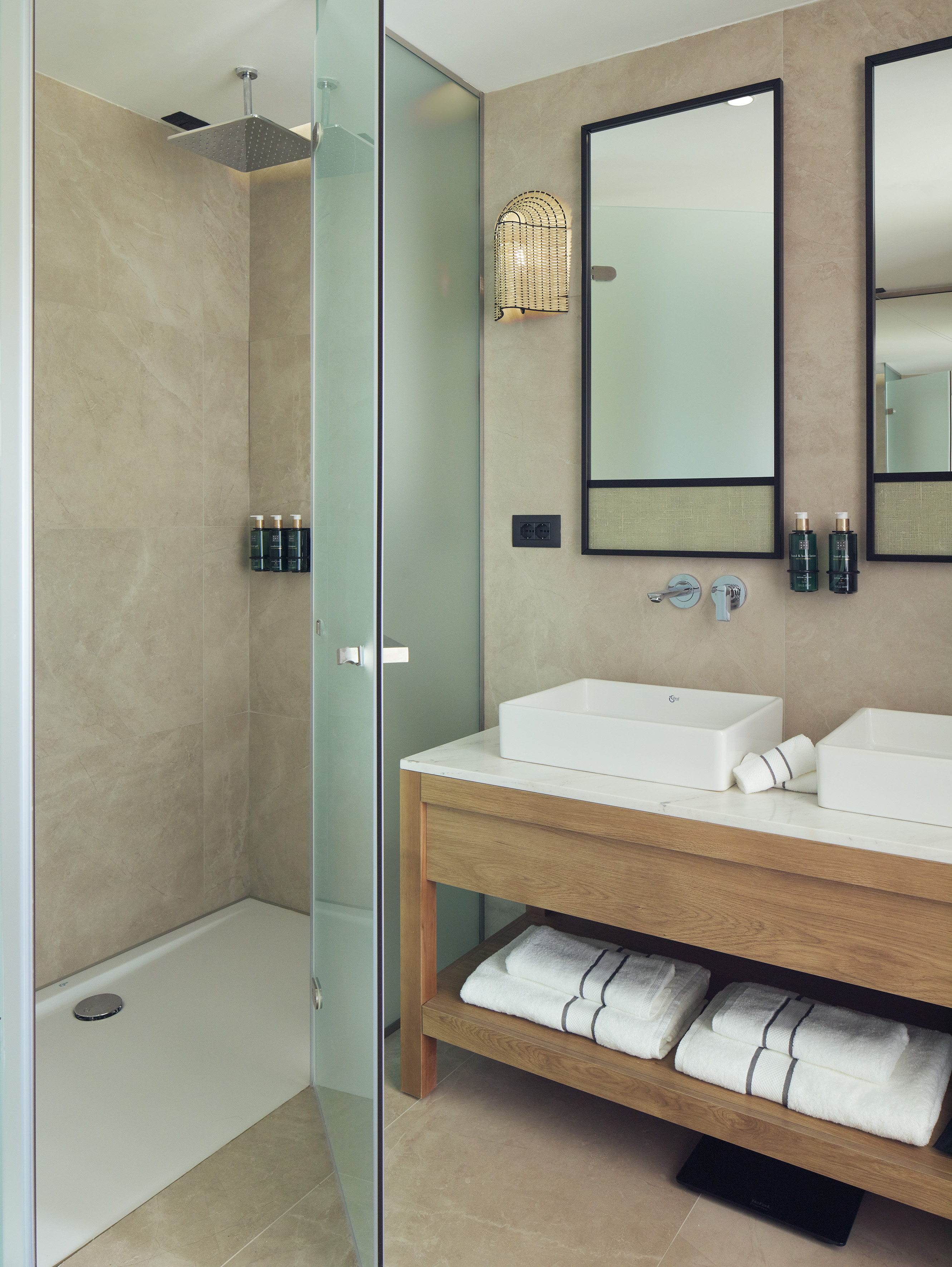 Modern bathroom with rainfall shower, glass enclosure, and double wood vanity.