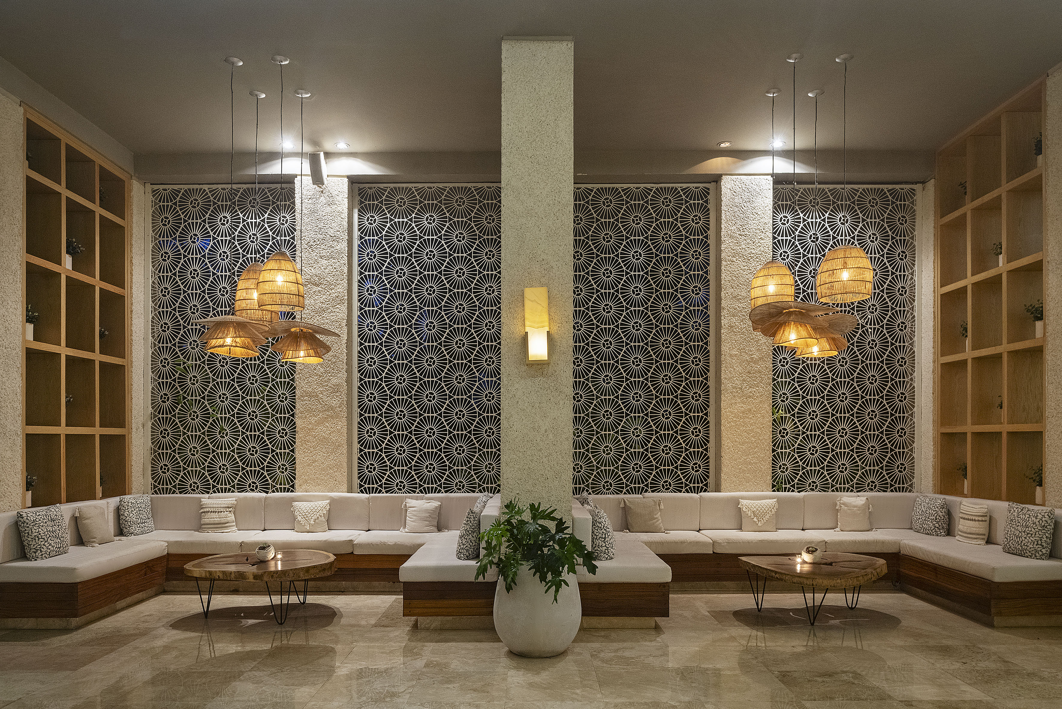 Modern resort lounge with geometric walls, beige seating, and rattan lights.