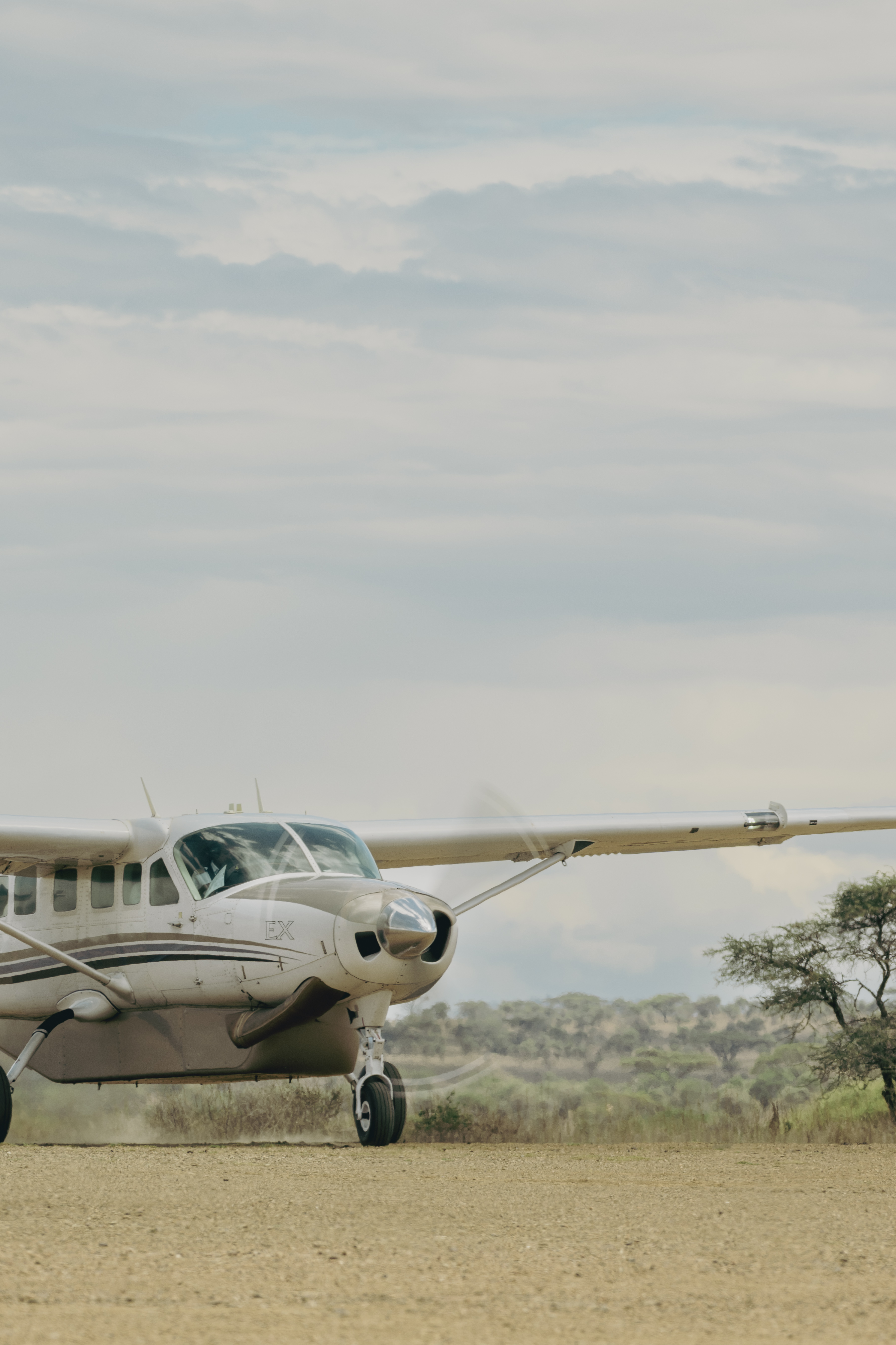 White propeller plane on a dirt airstrip, scenic safari aviation.