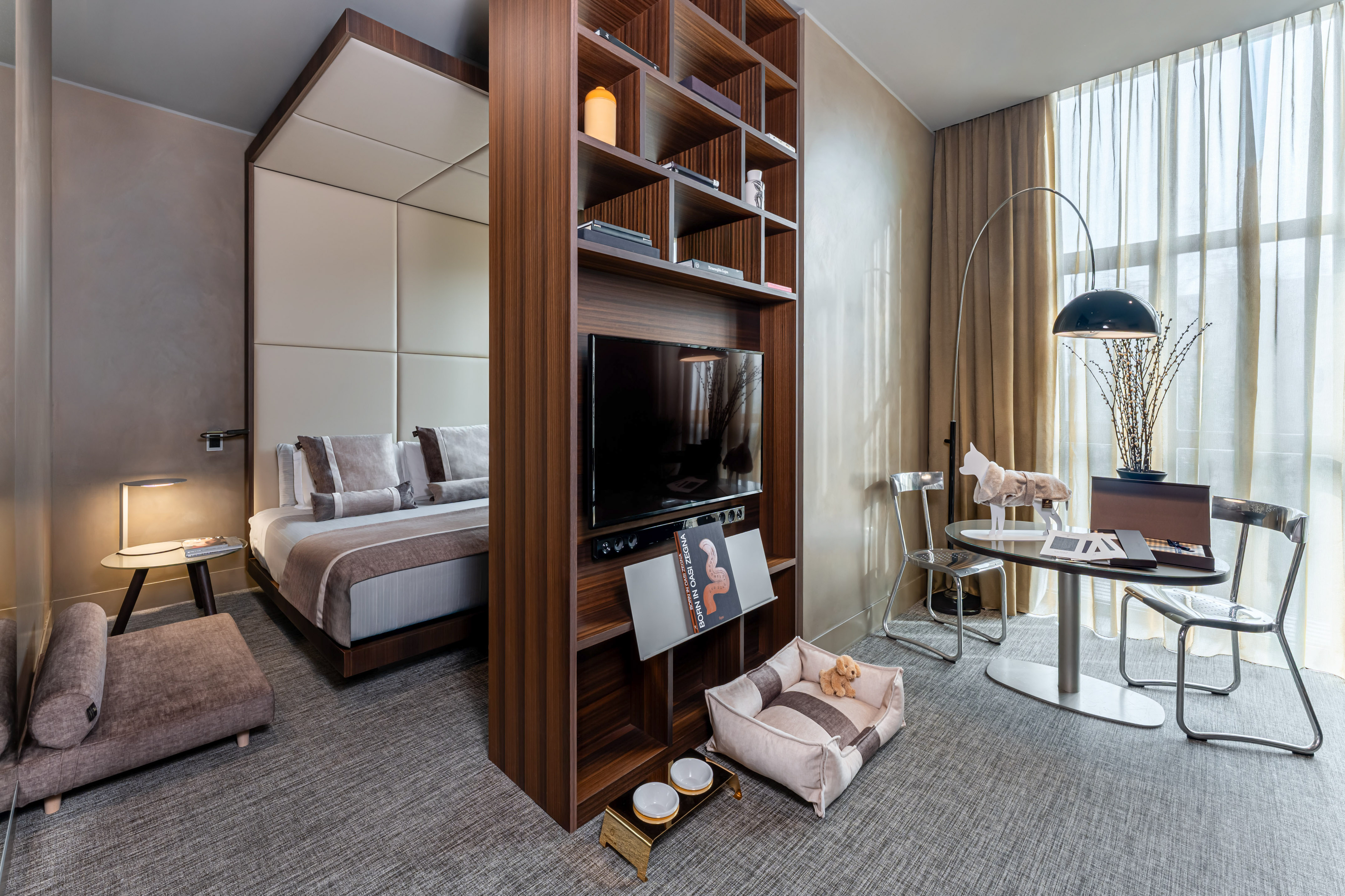 Stylish pet-friendly hotel room with bed, TV, dog bed, and work table.