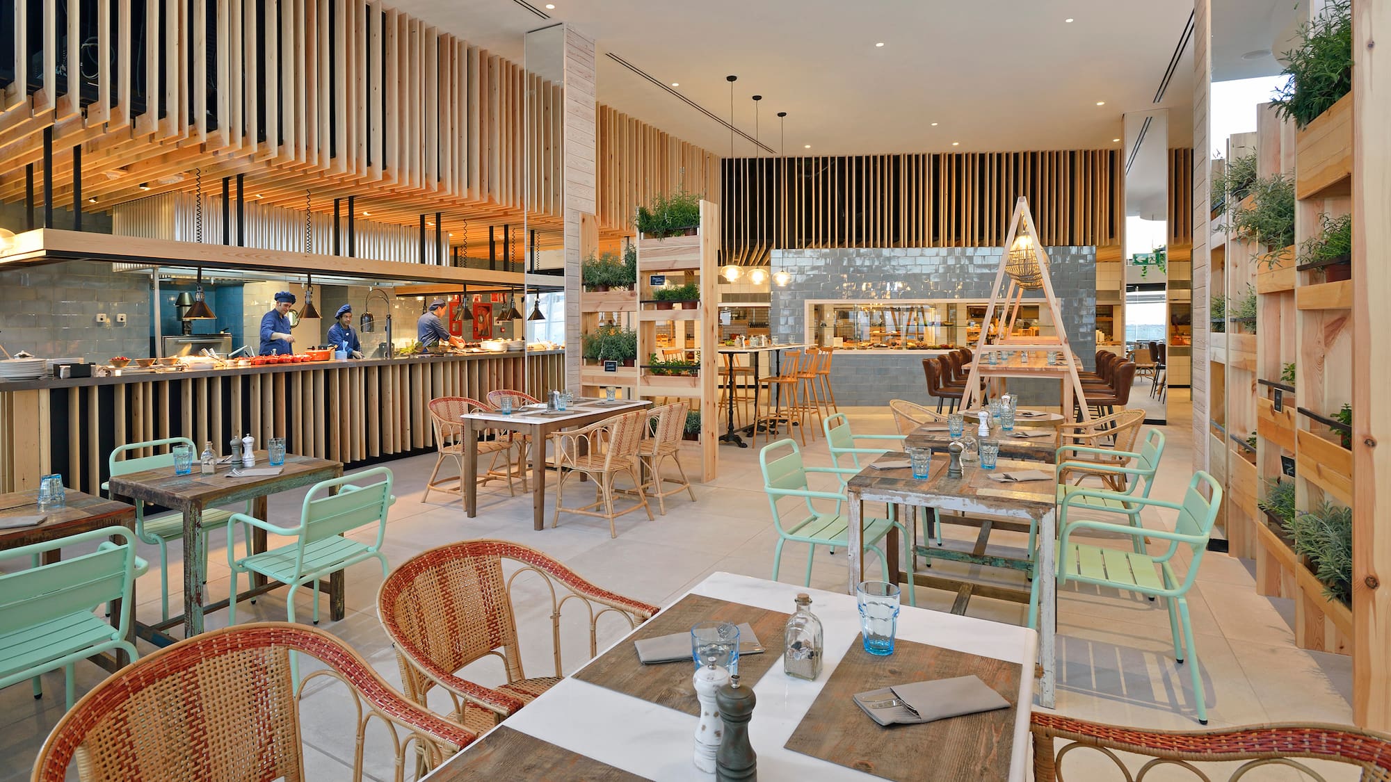 Open kitchen restaurant with modern wood slat design, buffet, and varied seating.