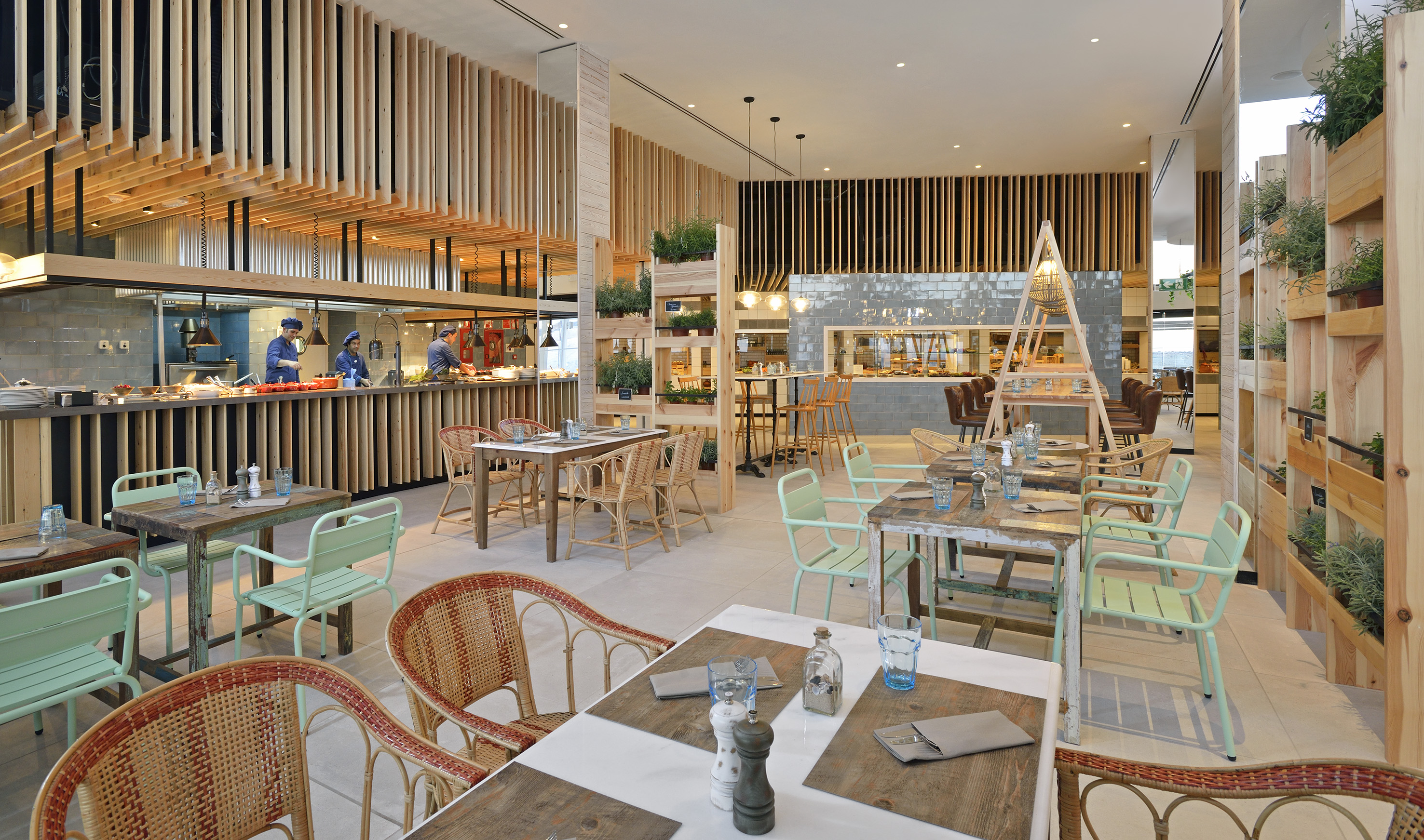 Open kitchen restaurant with modern wood slat design, buffet, and varied seating.