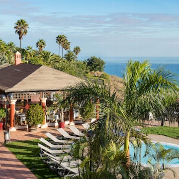 a pool and a gazebo with palm trees and a beach
