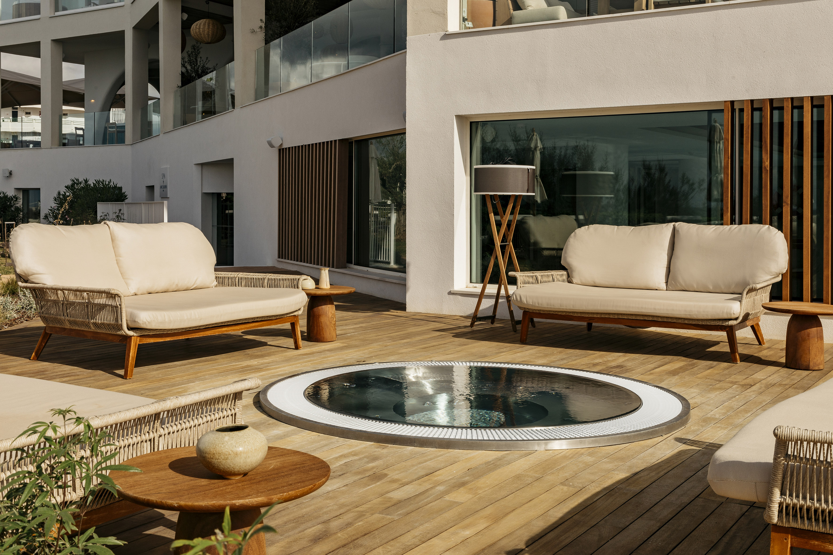 Resort patio with built-in hot tub, modern sofas, and wooden deck.