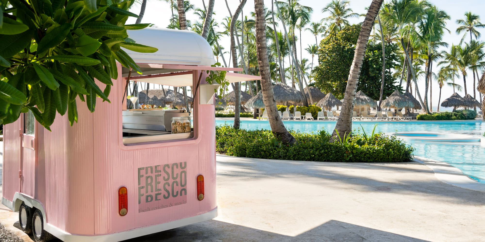 a pink food truck parked next to a pool