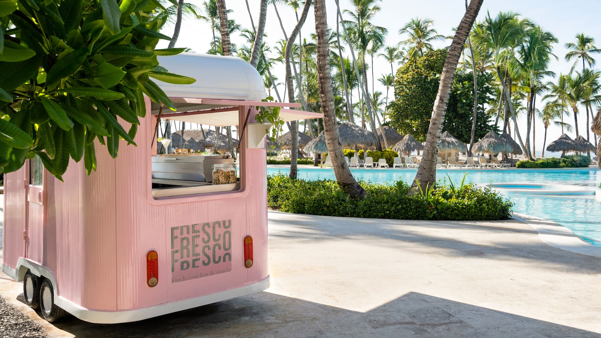a pink food truck parked next to a pool