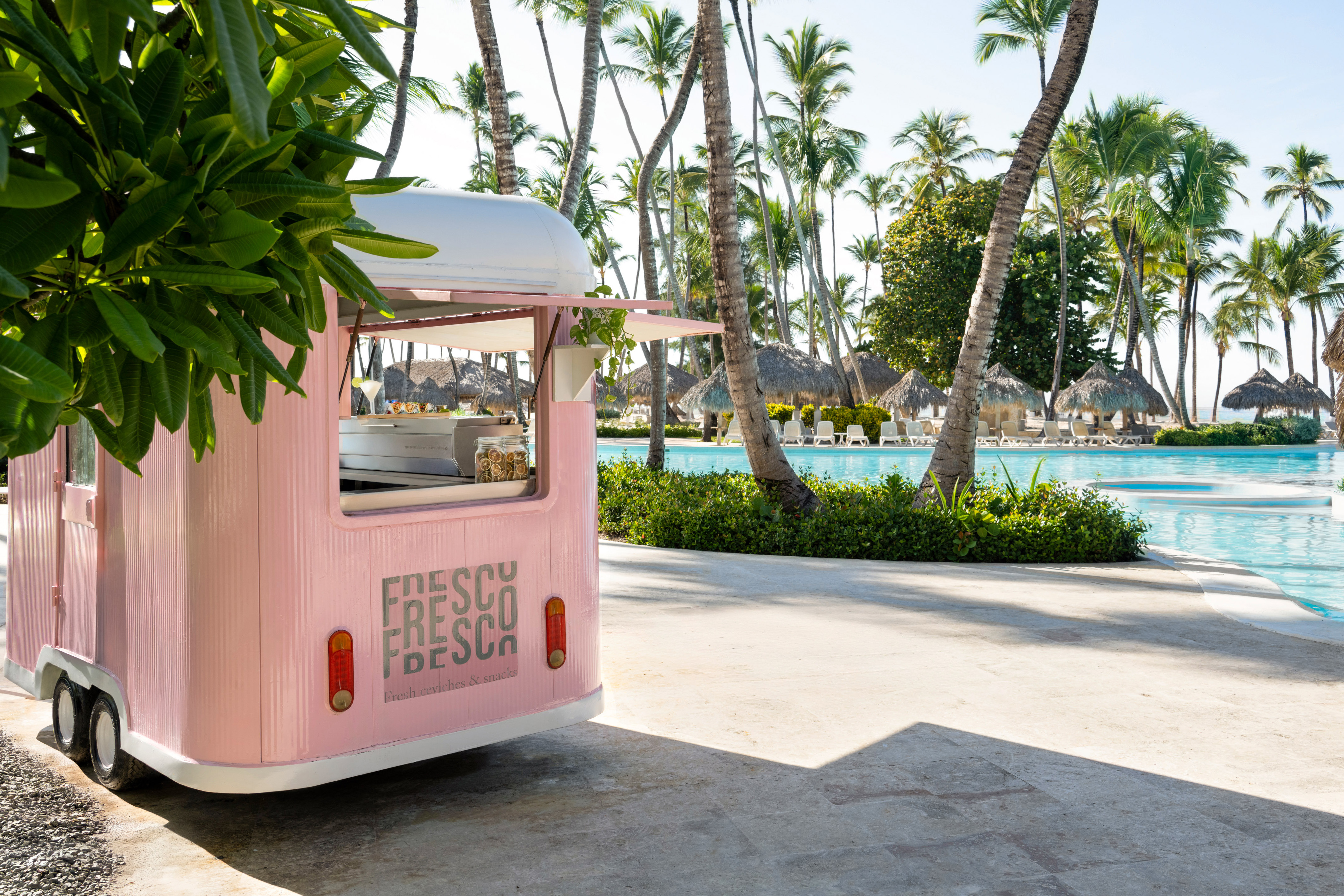 Pink Fresco Fresco ceviche truck by tropical pool and palm trees.