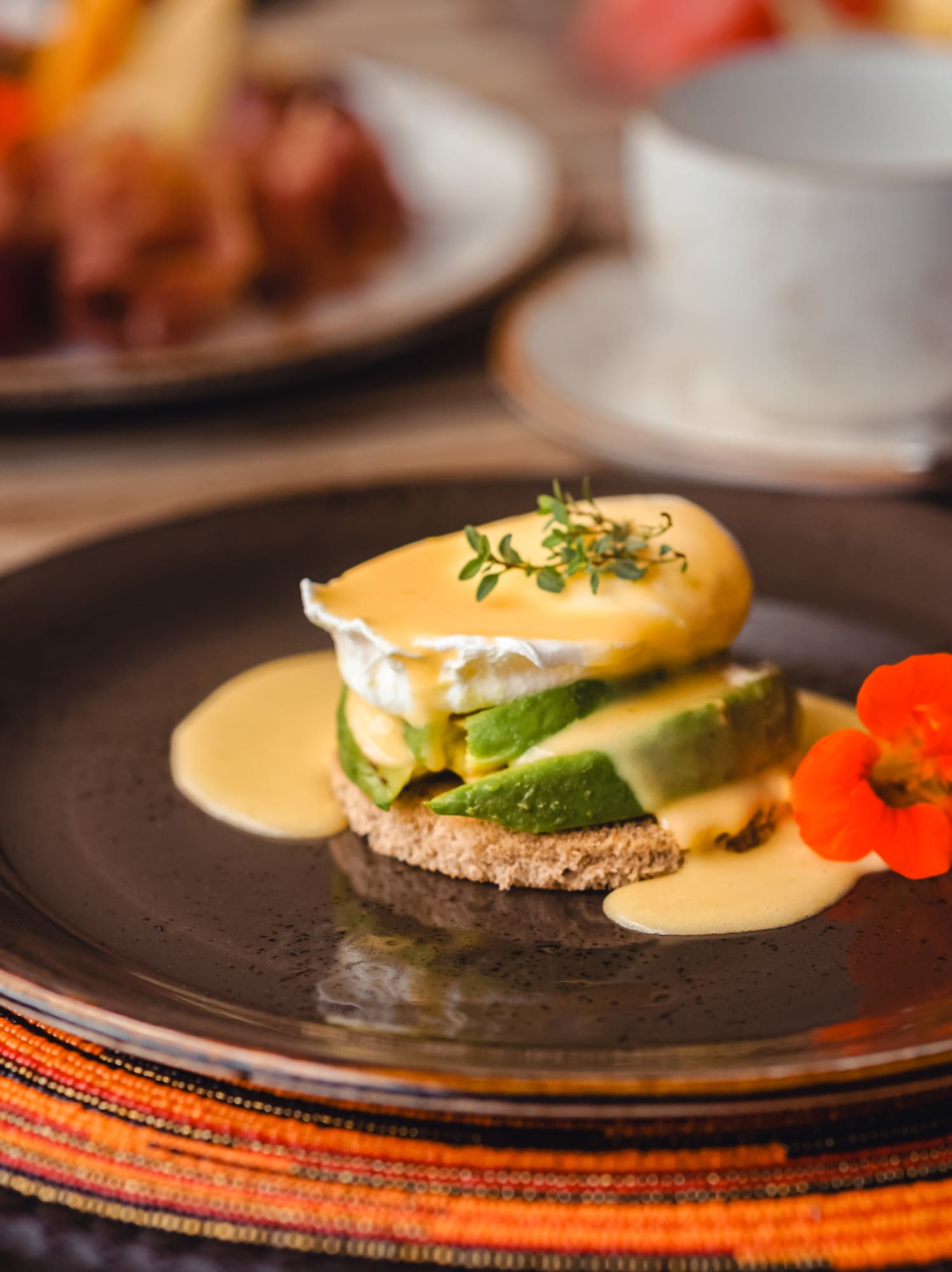 Avocado Eggs Benedict with poached egg, hollandaise, and nasturtium flower.