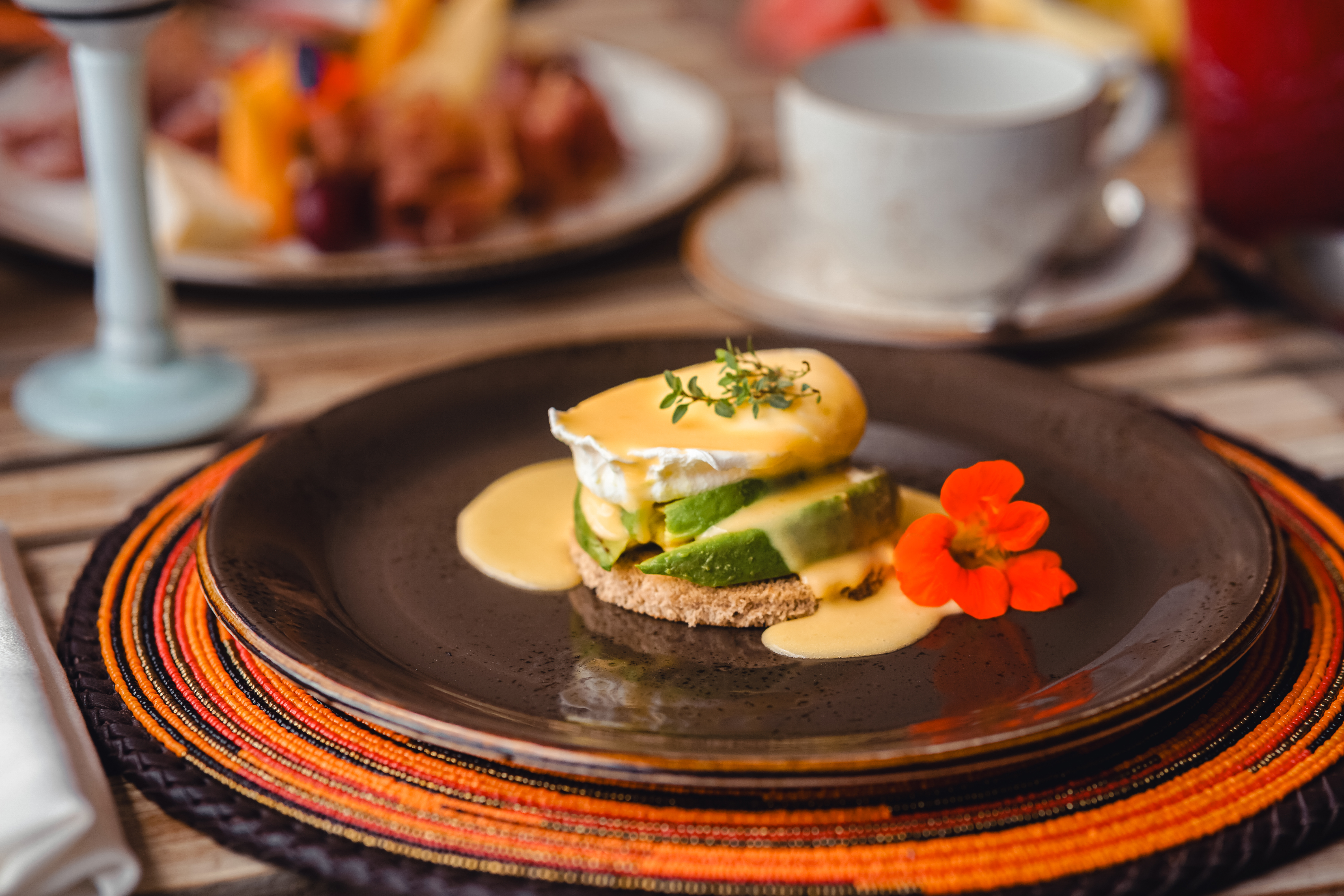 Avocado Eggs Benedict with poached egg, hollandaise, and nasturtium flower.