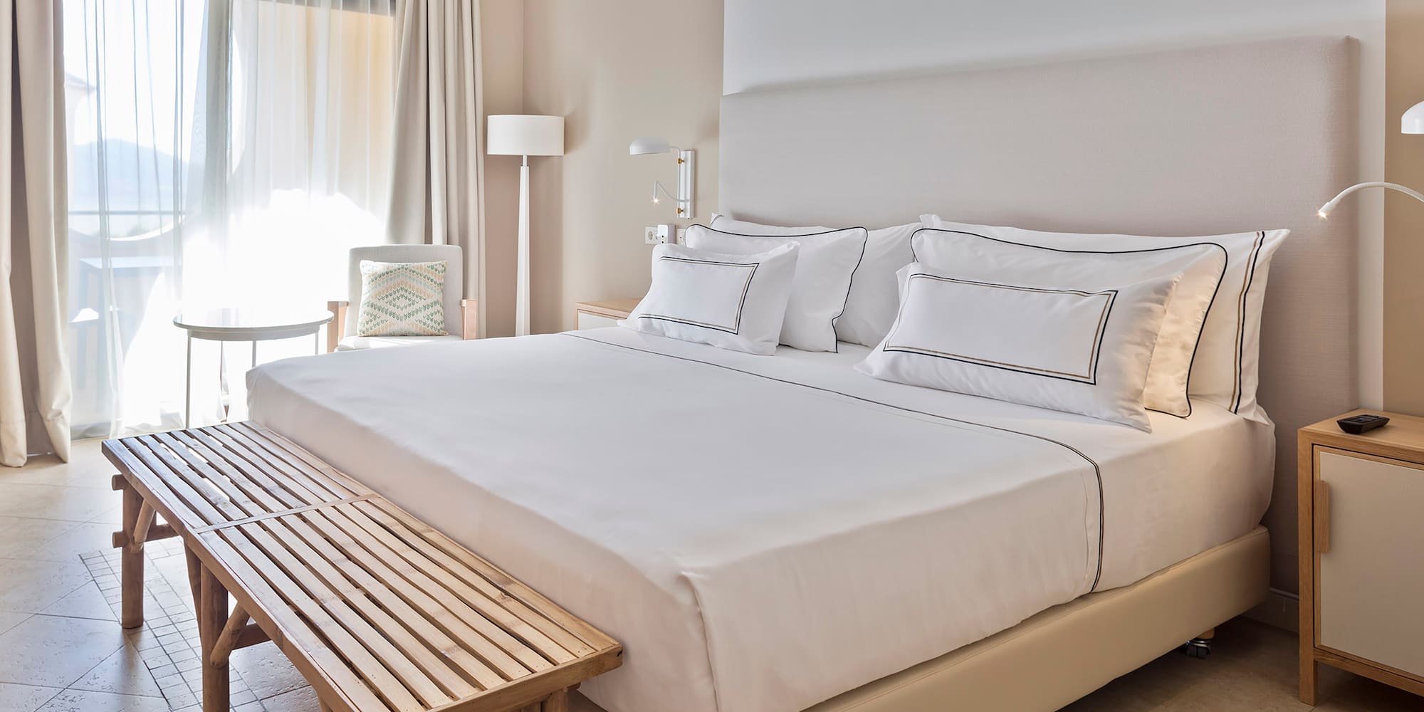 a bed with white sheets and a bench