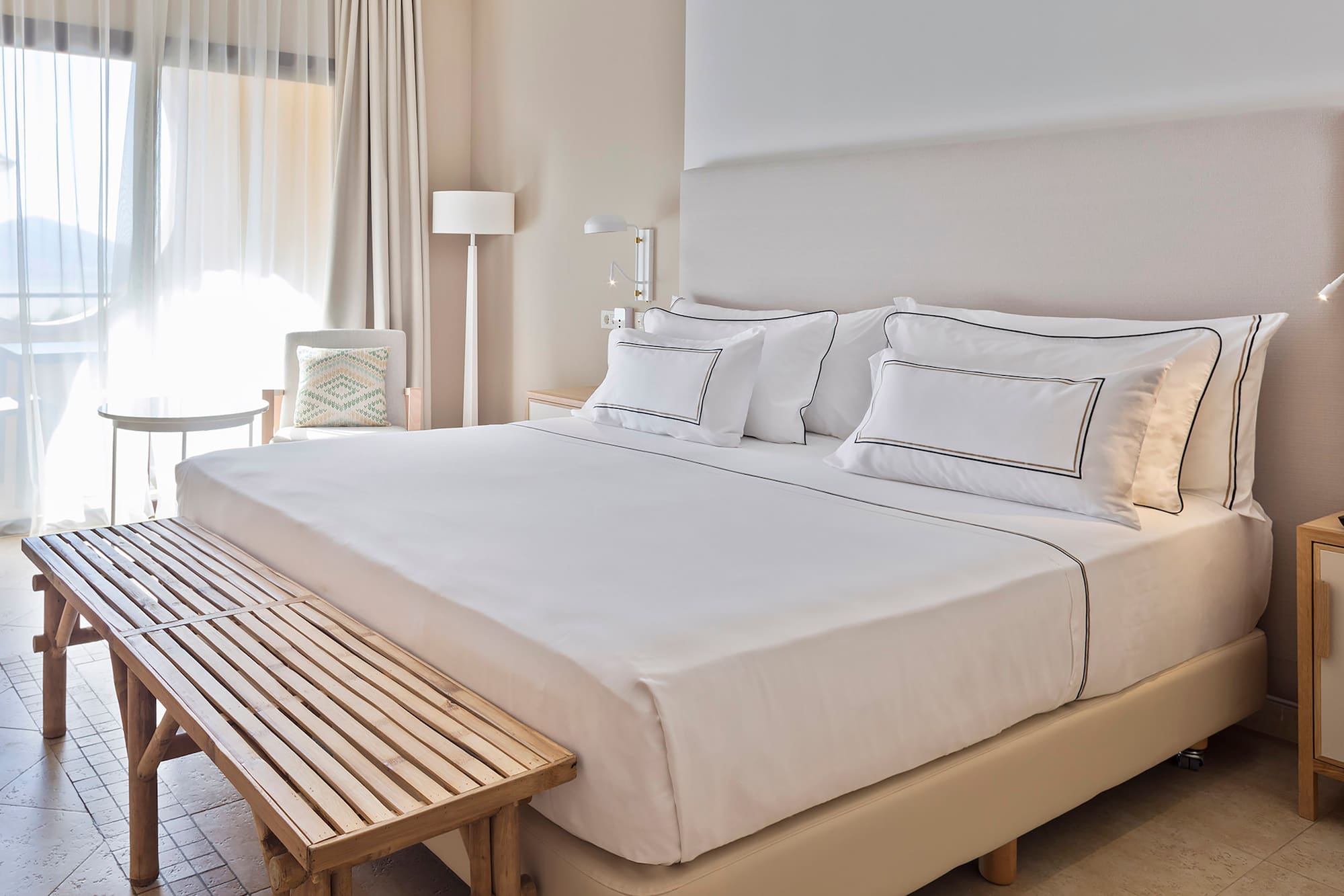 a bed with white sheets and a bench