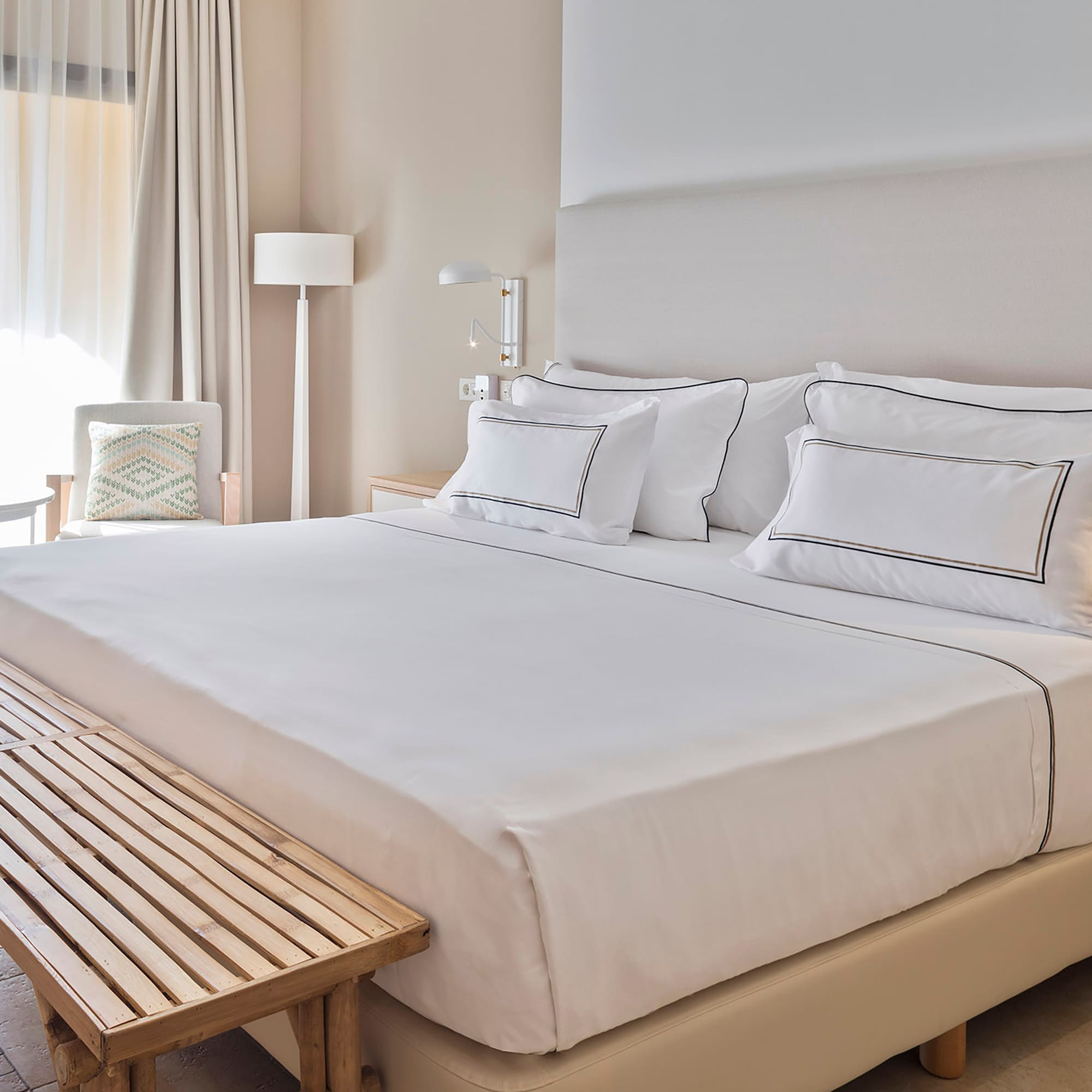 a bed with white sheets and a bench