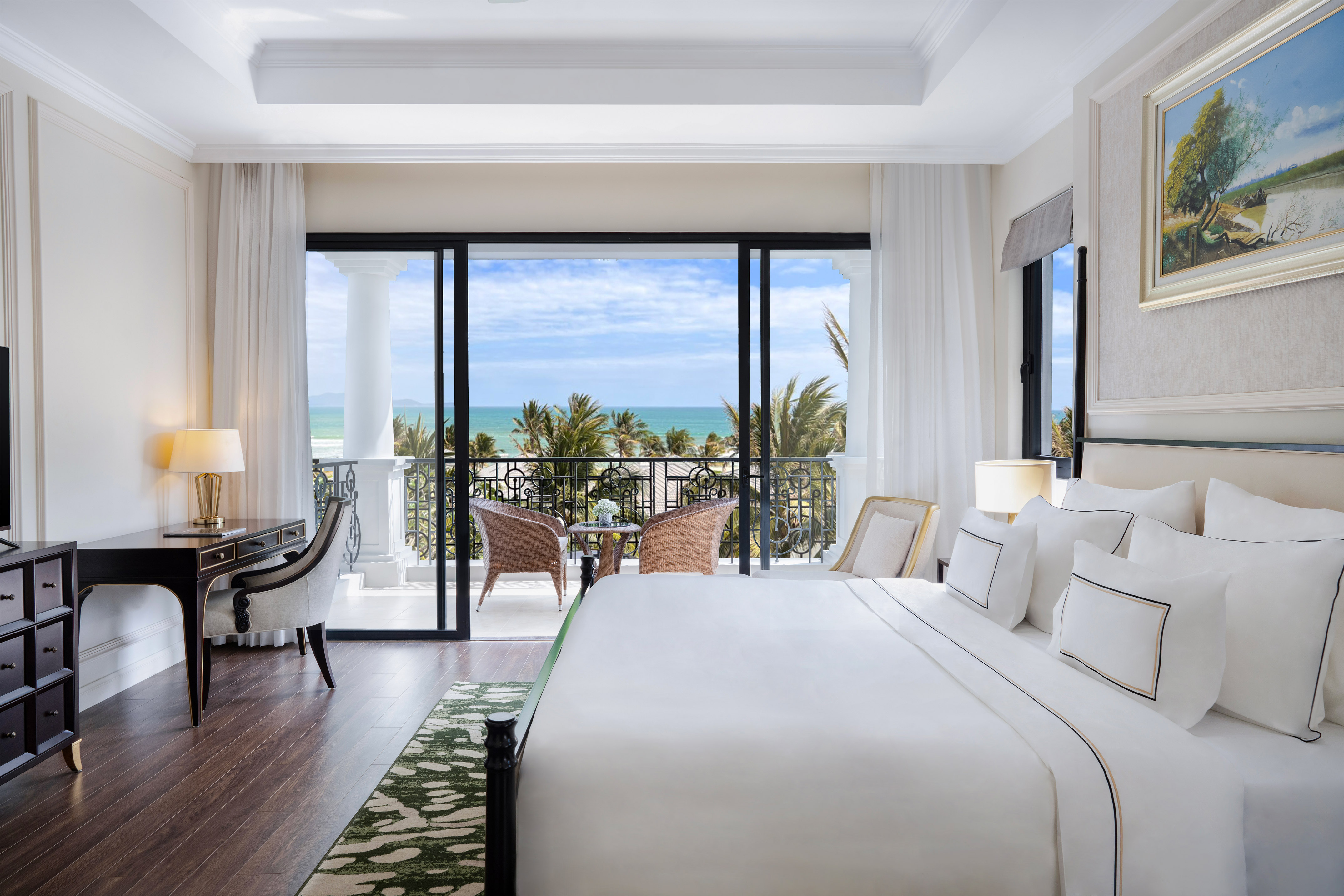 Luxury hotel bedroom with ocean view balcony and palm trees.