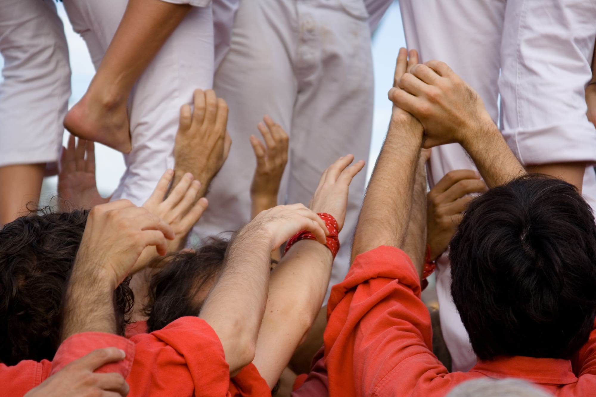 Manos y pies de castellers construyendo torre humana tradicional.