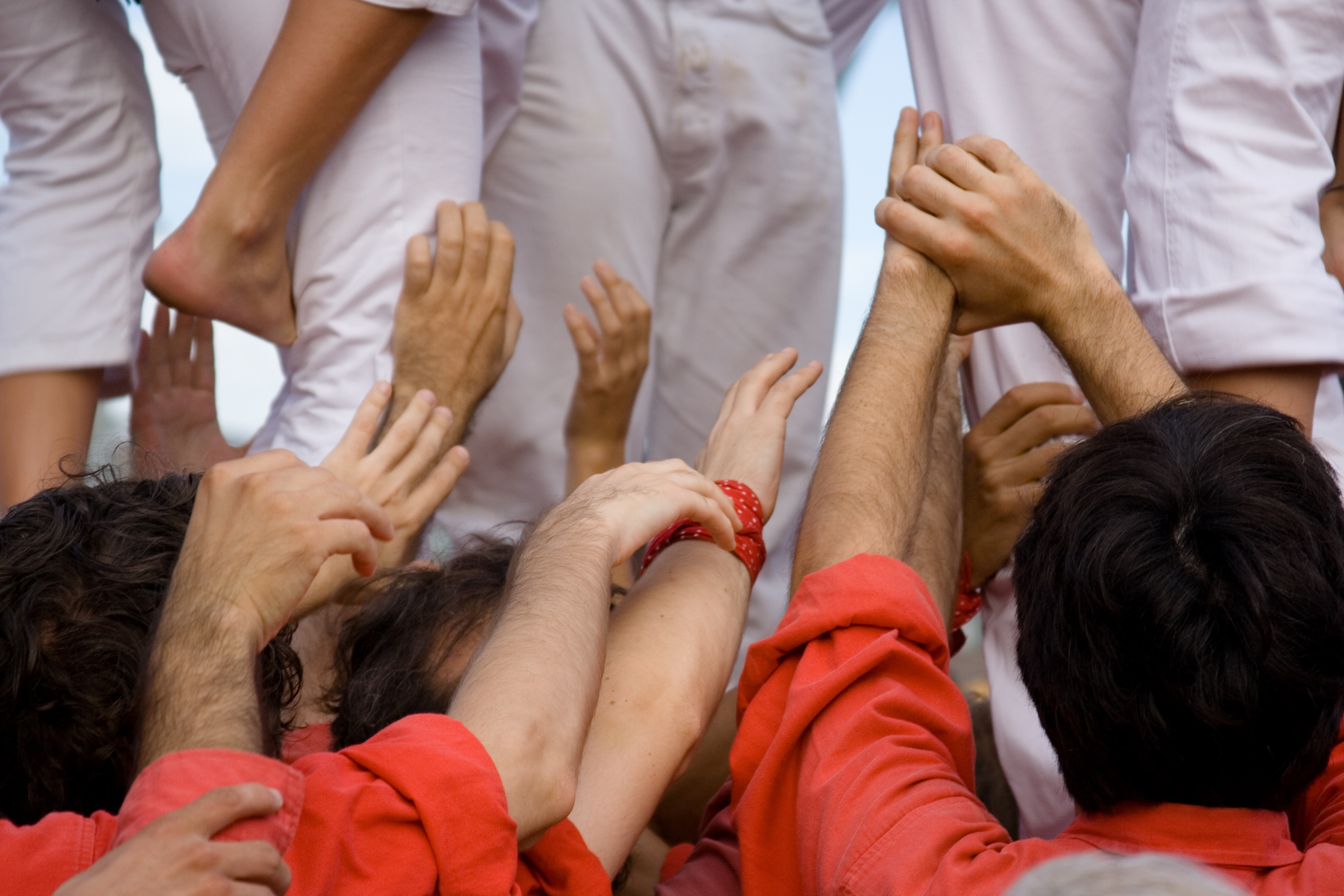 Manos y pies de castellers construyendo torre humana tradicional.