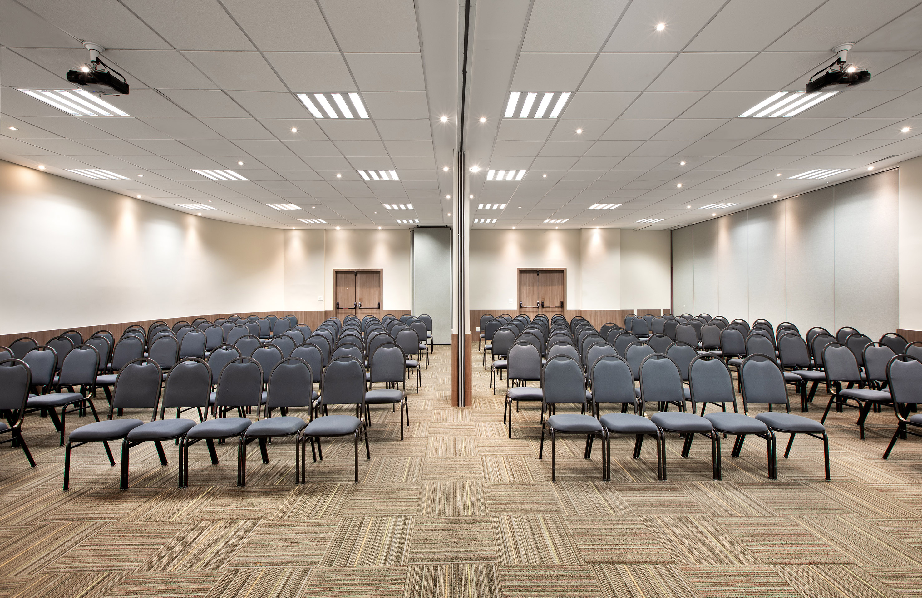 Spacious conference room with gray chairs, patterned carpet, and ceiling projectors.