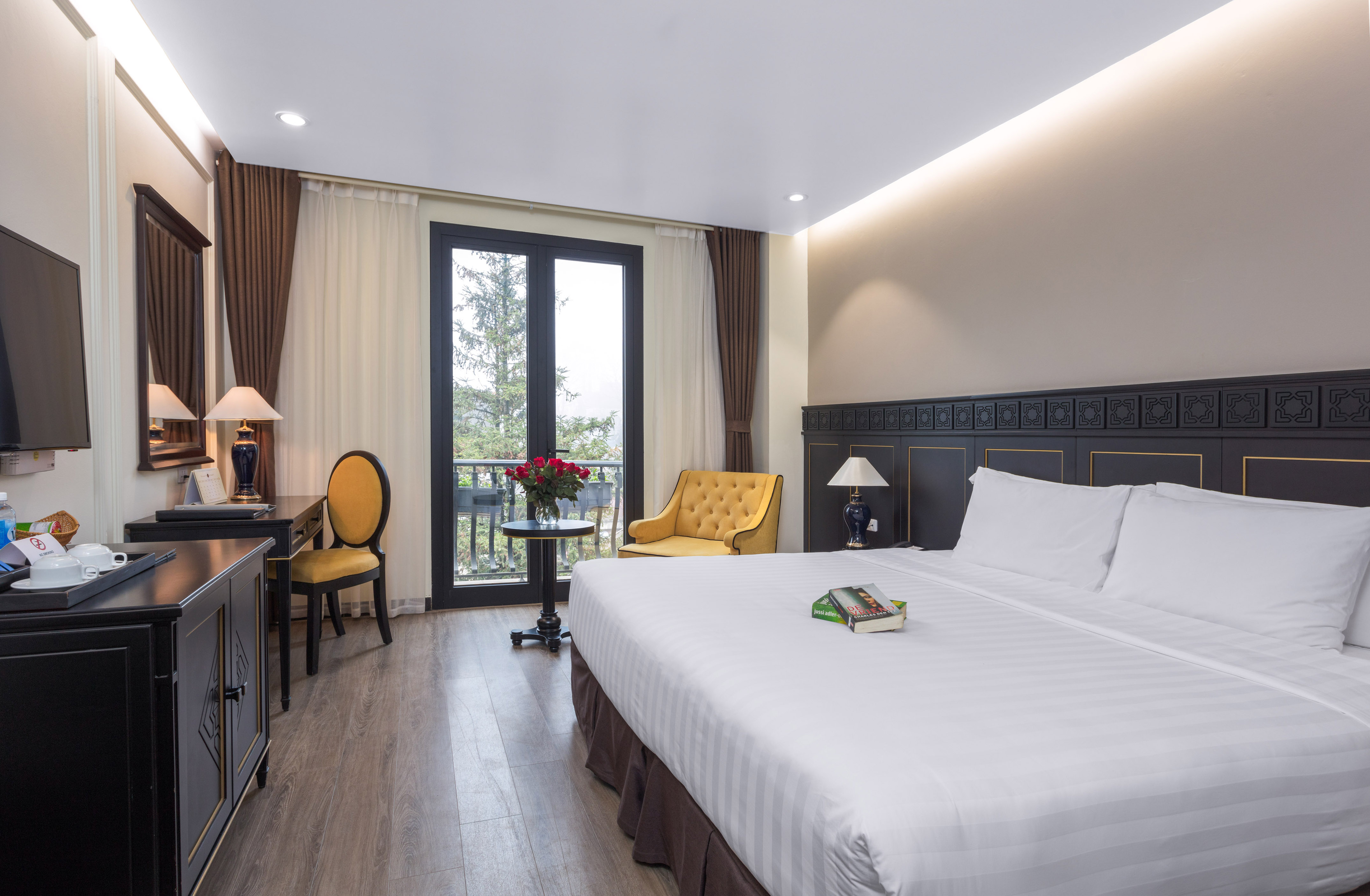 Elegant hotel room with king bed, mountain view balcony, desk, and armchair.