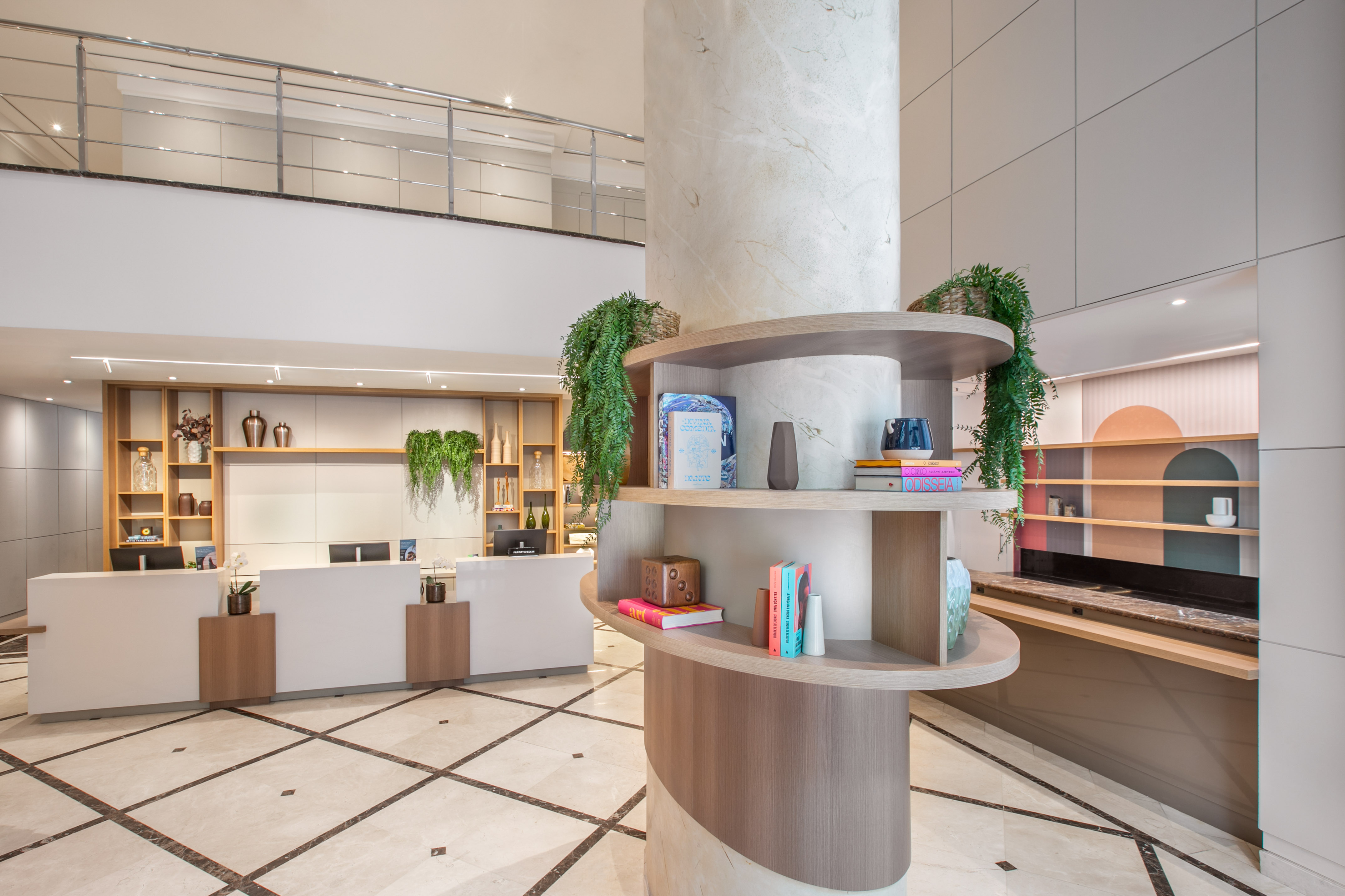 Elegant hotel reception with white desk, marble pillar, and curated shelving.