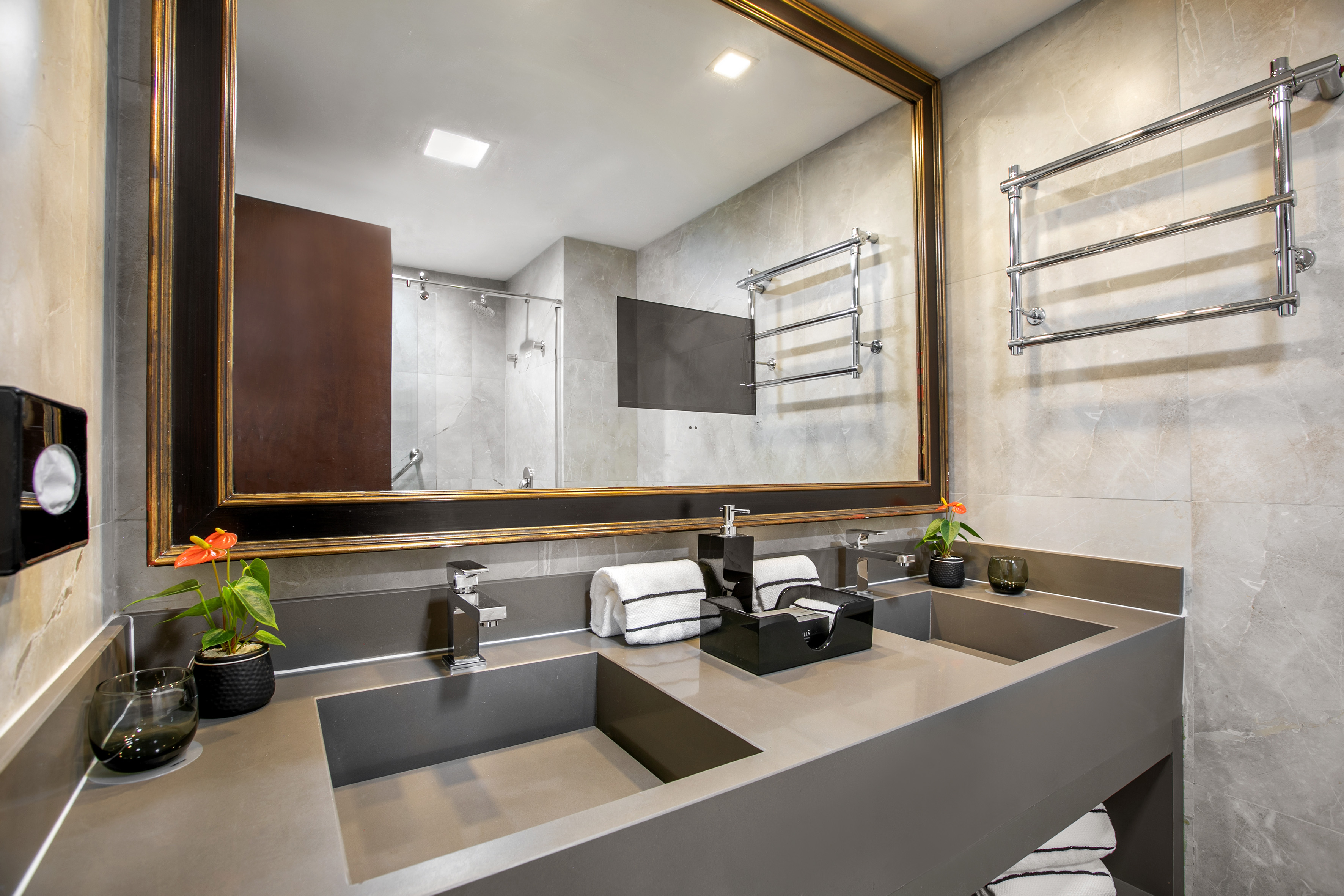 Luxury bathroom with double grey vanity, large mirror, chrome towel warmer.