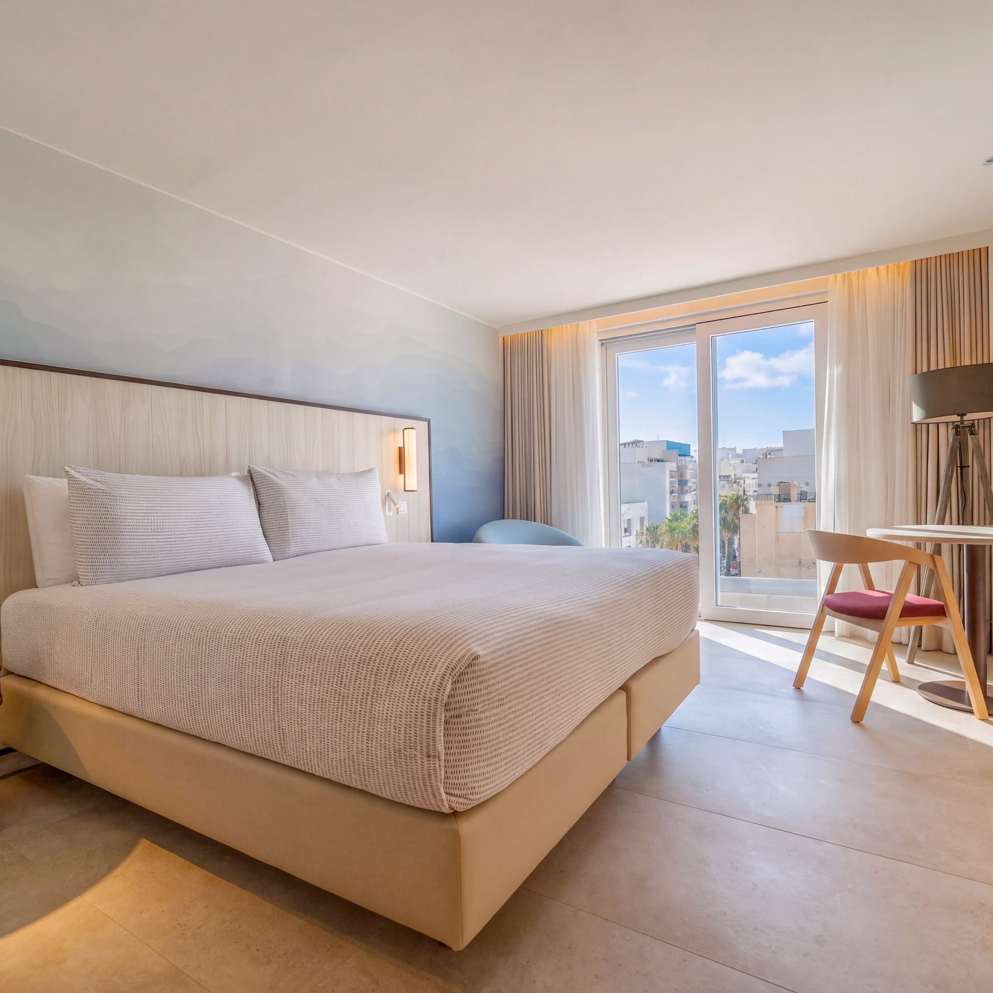 Modern hotel bedroom with king bed, city view balcony, and chic design.