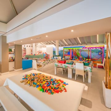 a room with white tables and white chairs and a table with colorful blocks