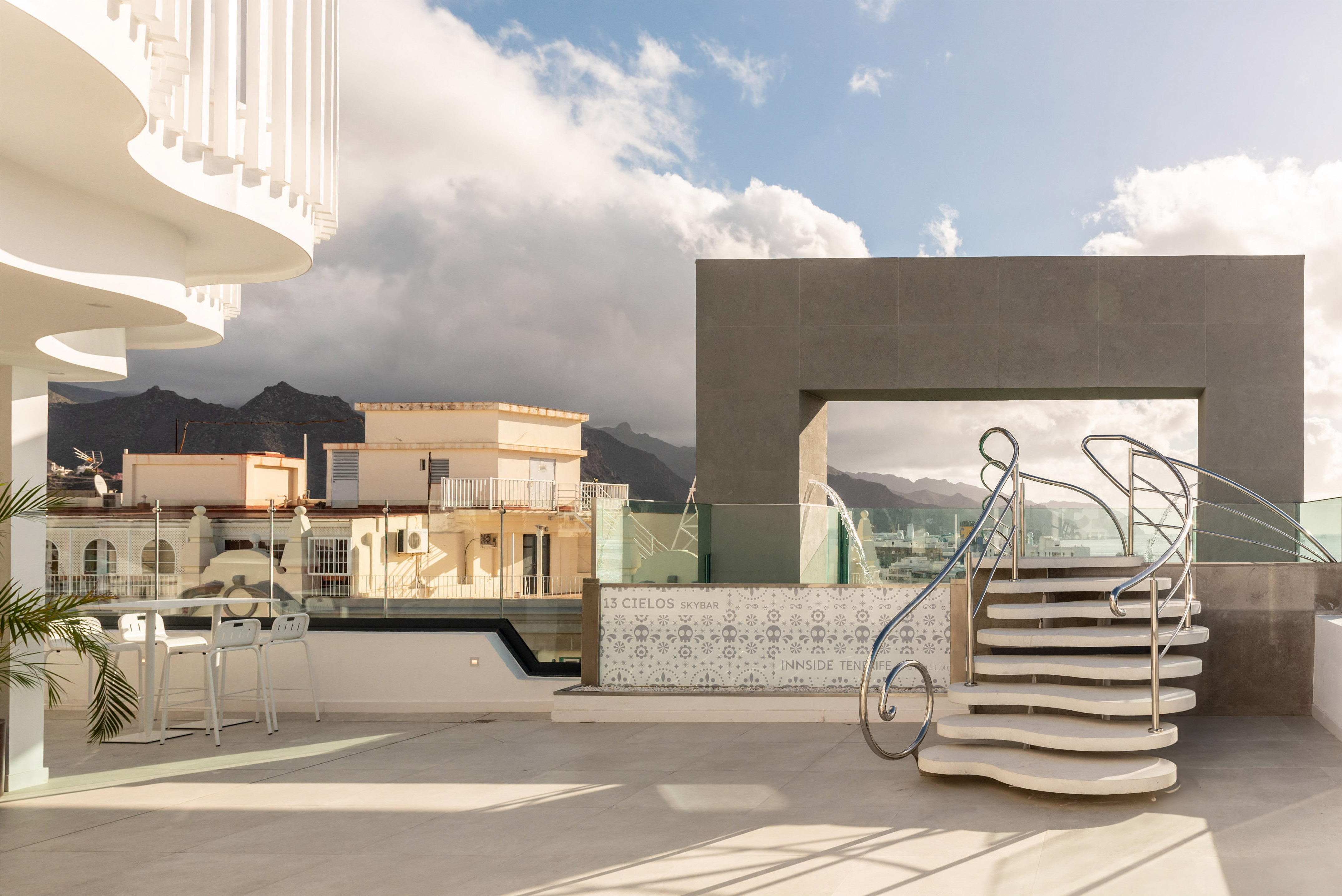 Tenerife rooftop skybar: modern architecture, curved stairs, and mountain views.