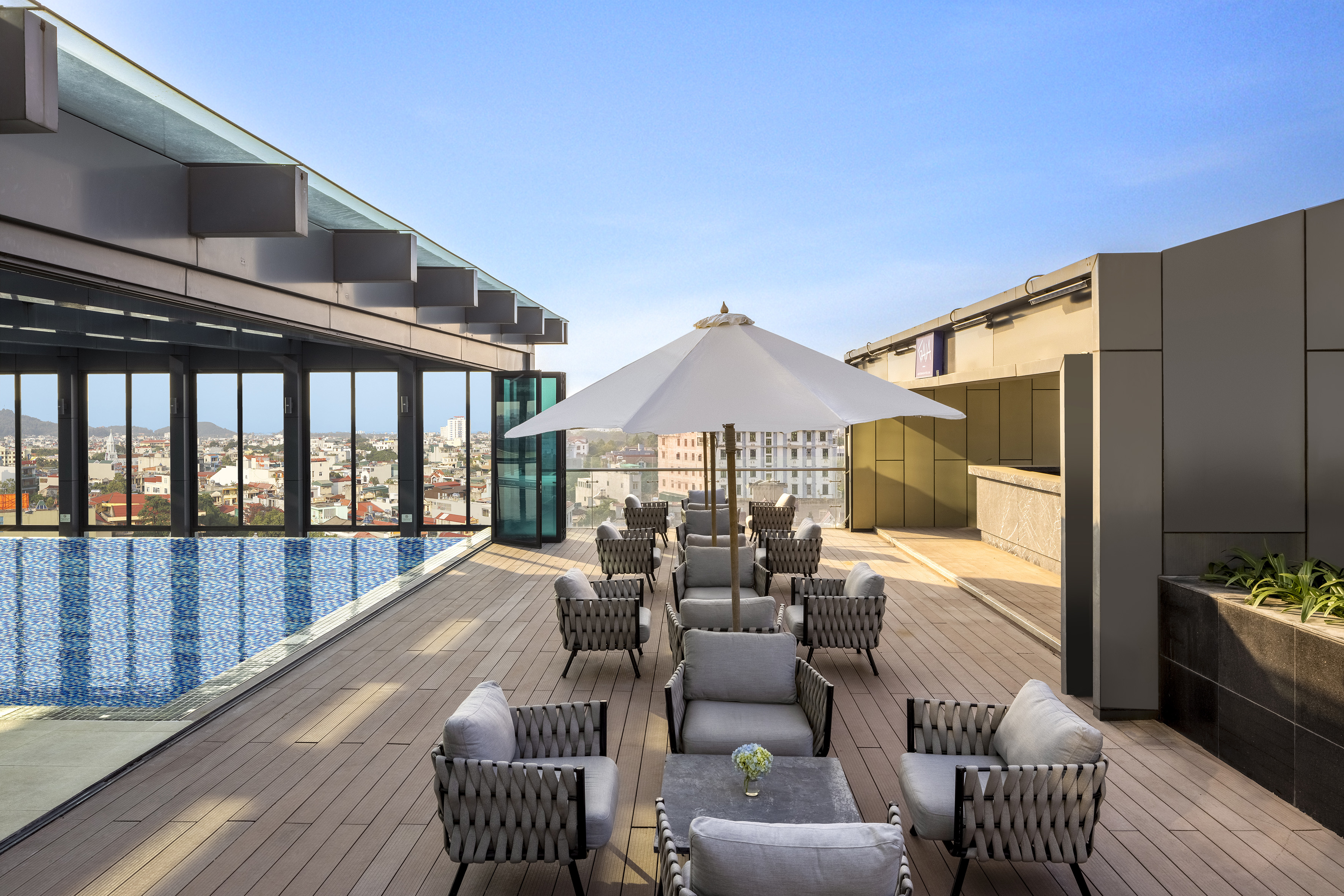 Rooftop infinity pool, modern outdoor lounge seating, city view.