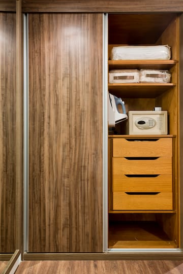 a closet with a microwave and a wood cabinet