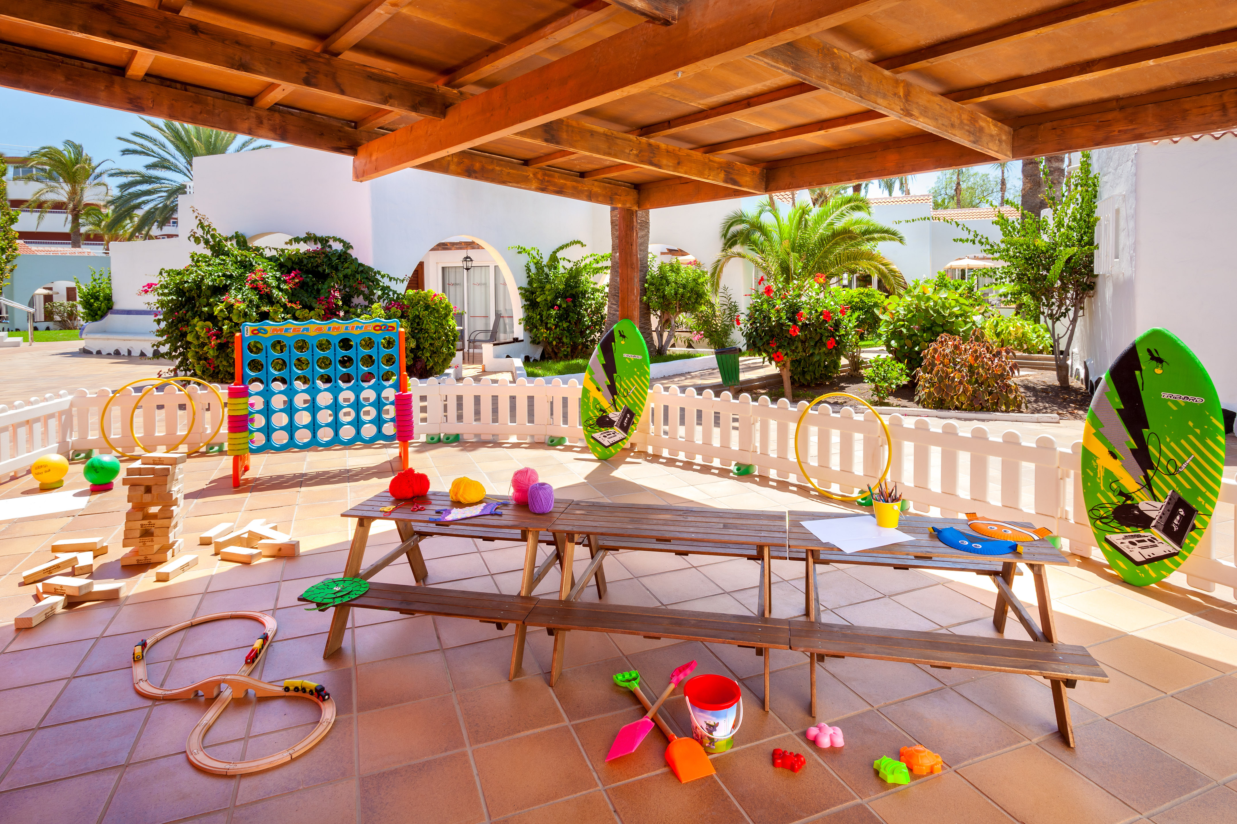 Resort kids' play area with giant games, train set, craft table, and toys.
