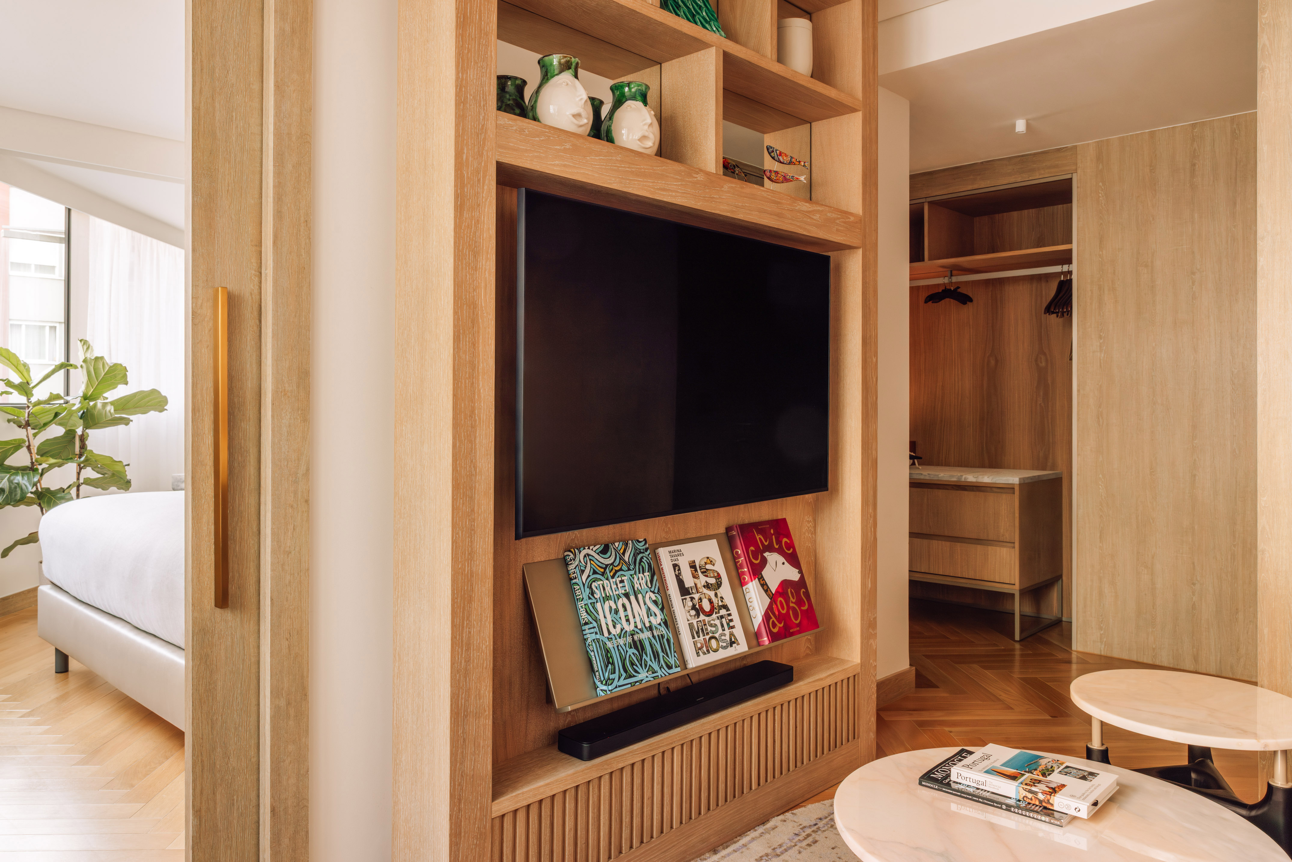 Modern wooden partition with TV, books, decor, dividing bedroom from lounge.