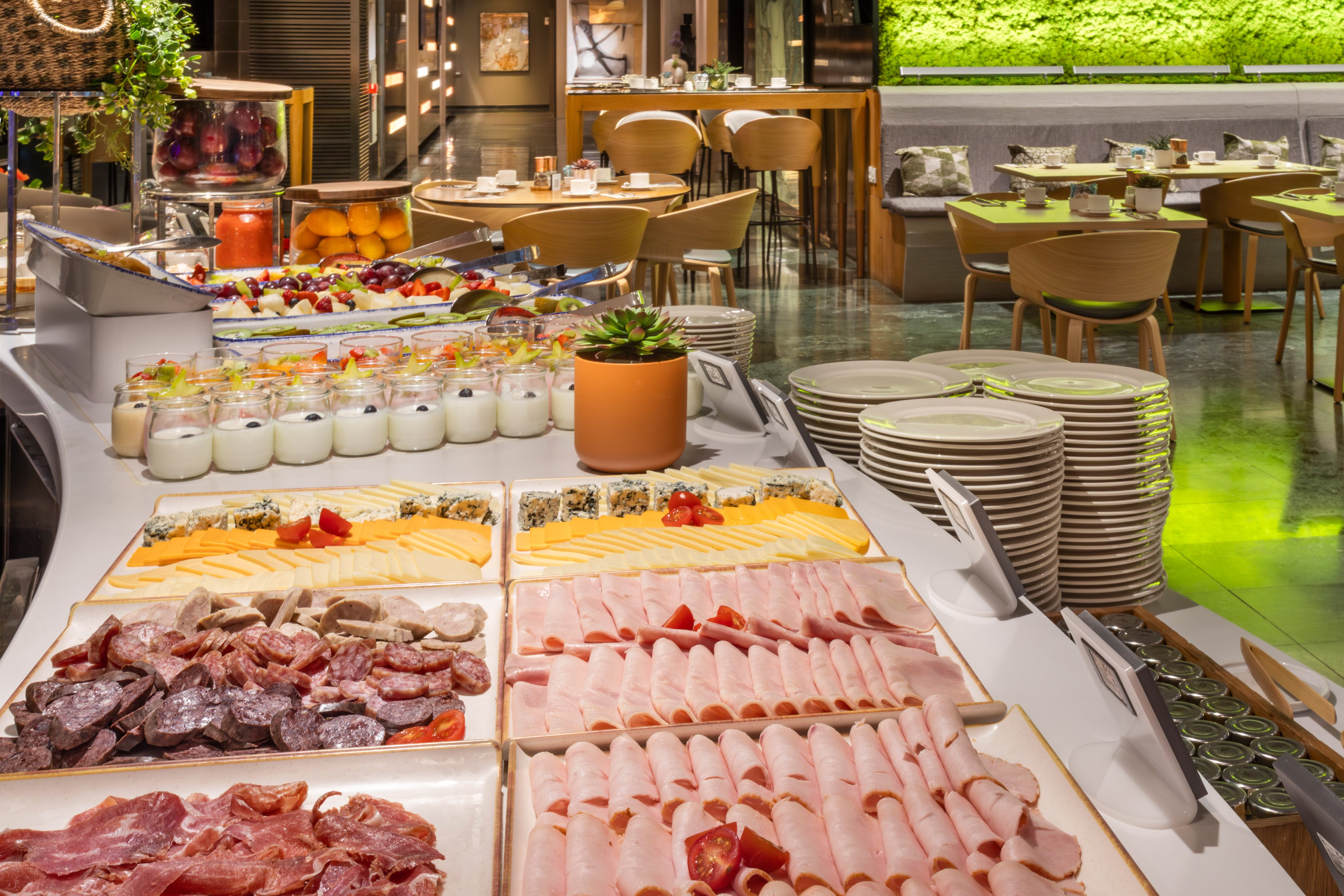 Hotel breakfast buffet featuring fruits, yogurts, cheeses, and cold cuts.