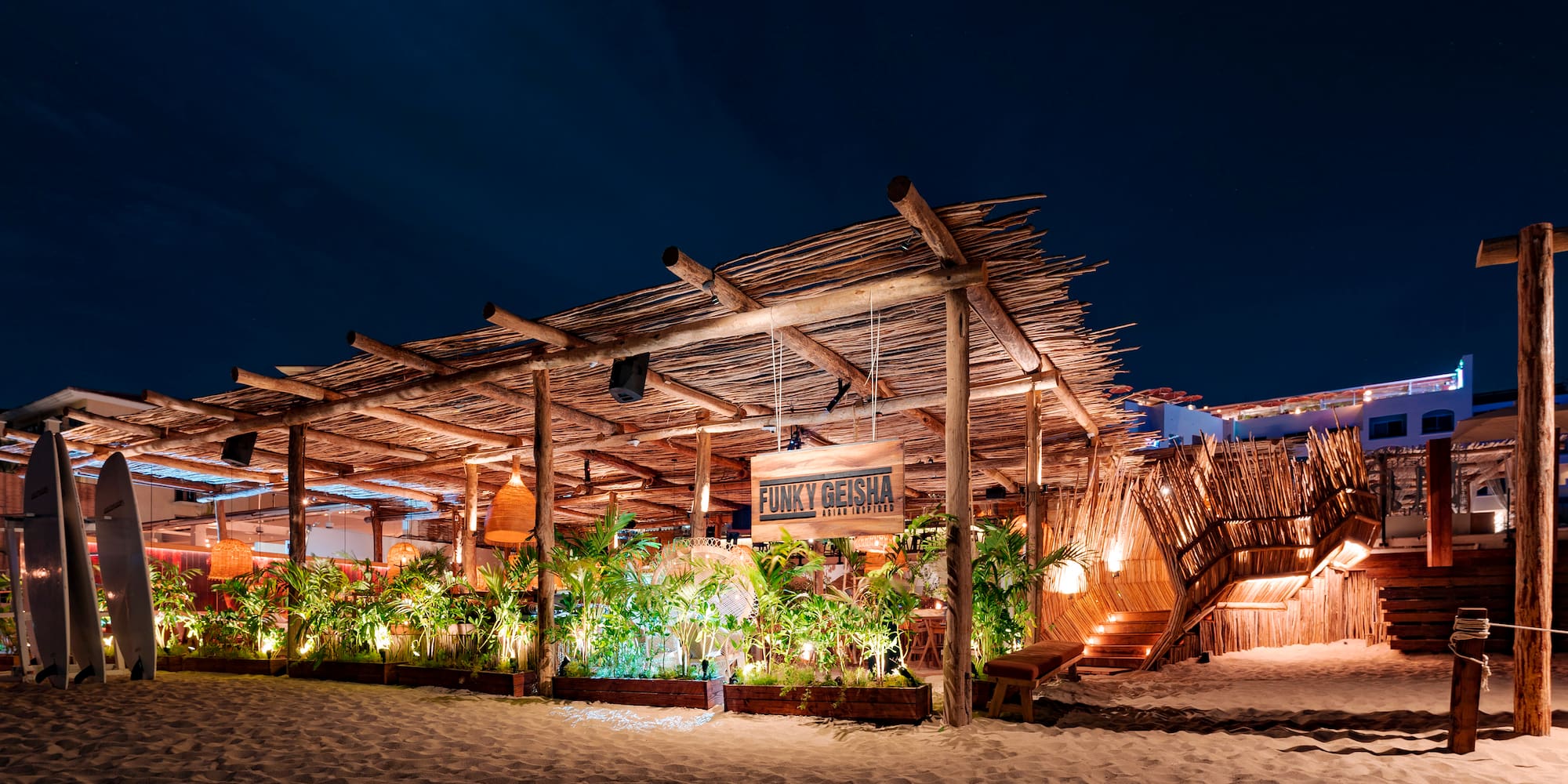 a building with a wooden structure and plants on the beach
