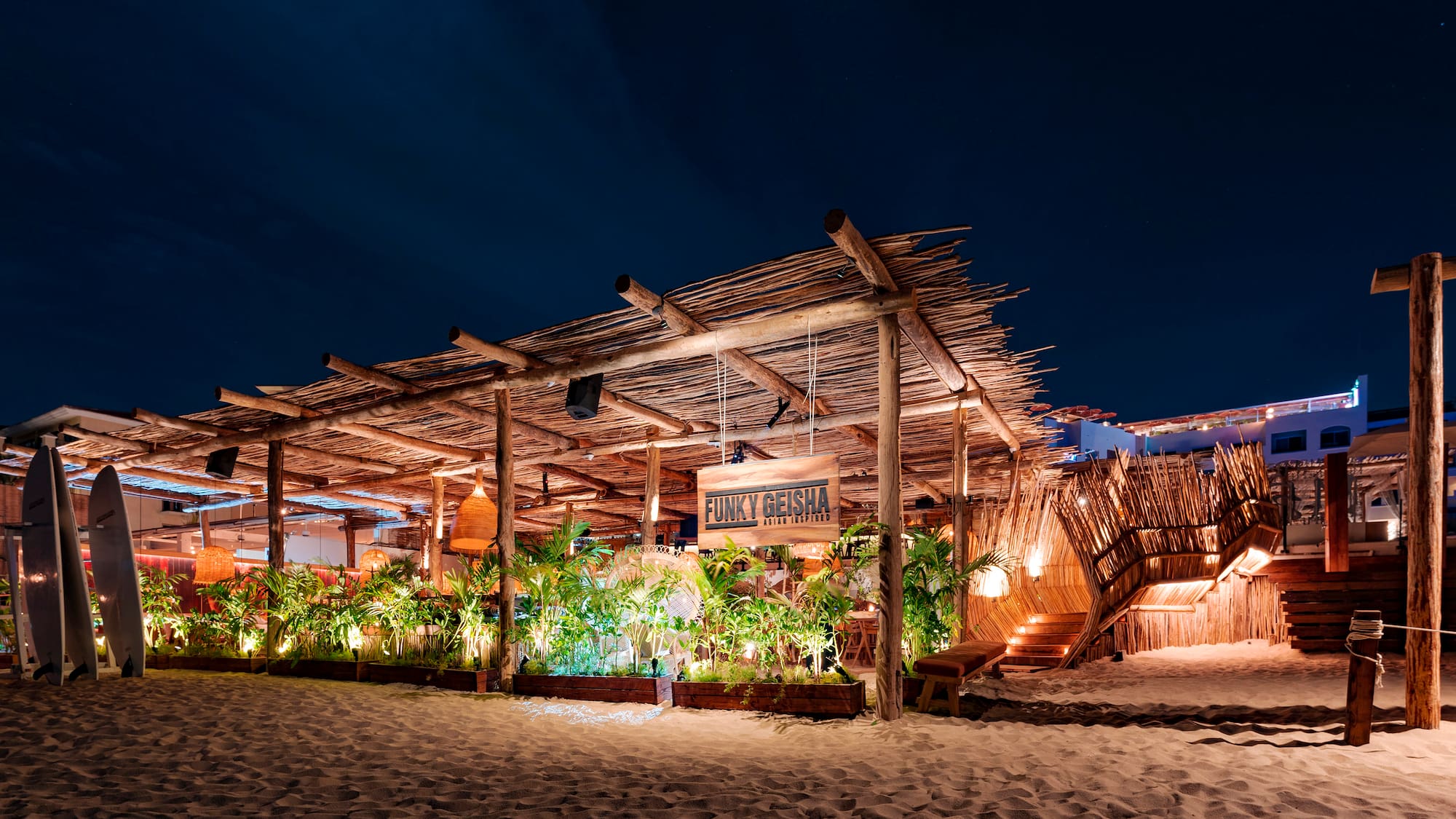 a building with a wooden structure and plants on the beach