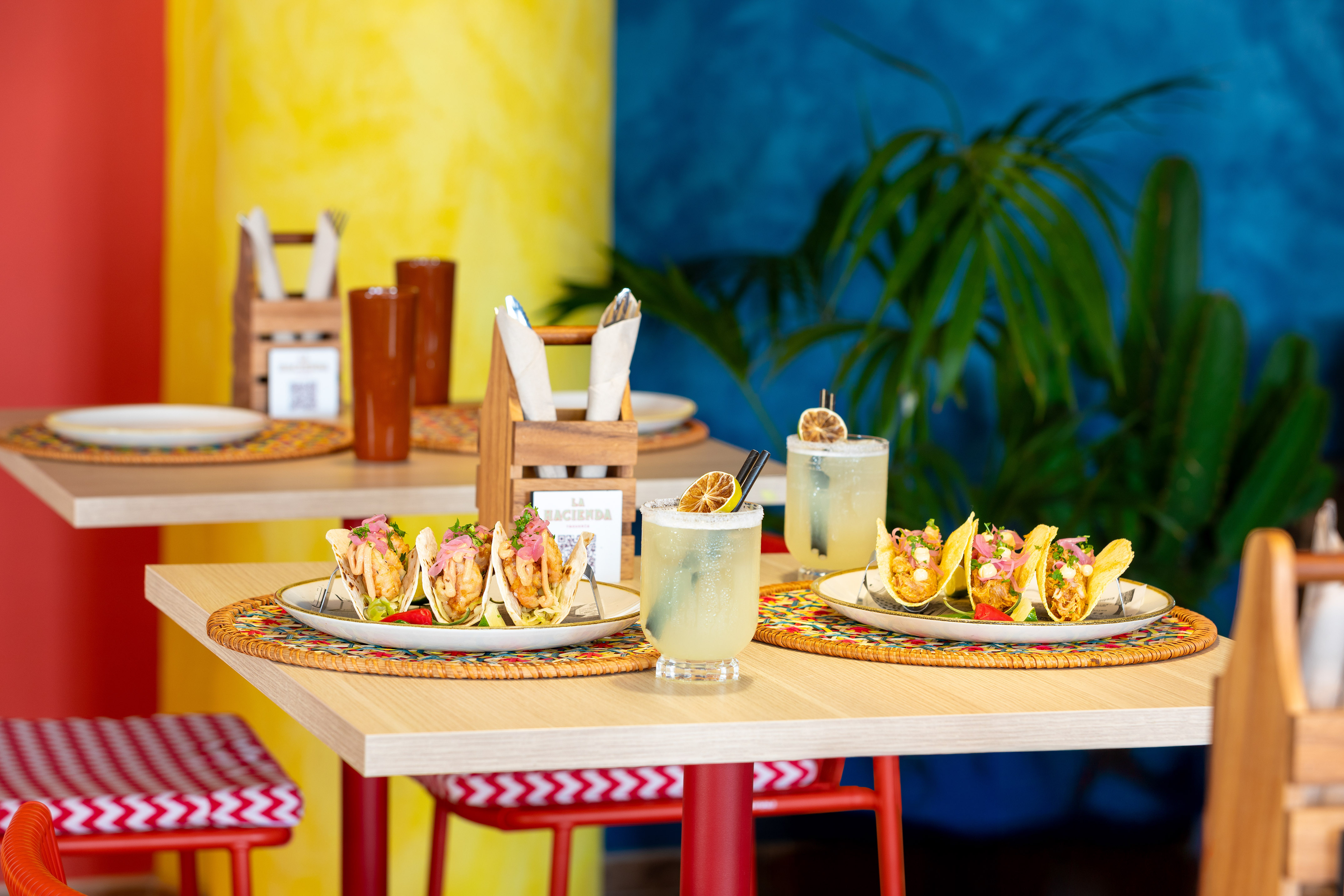 Vibrant restaurant table with two plates of tacos and margaritas.