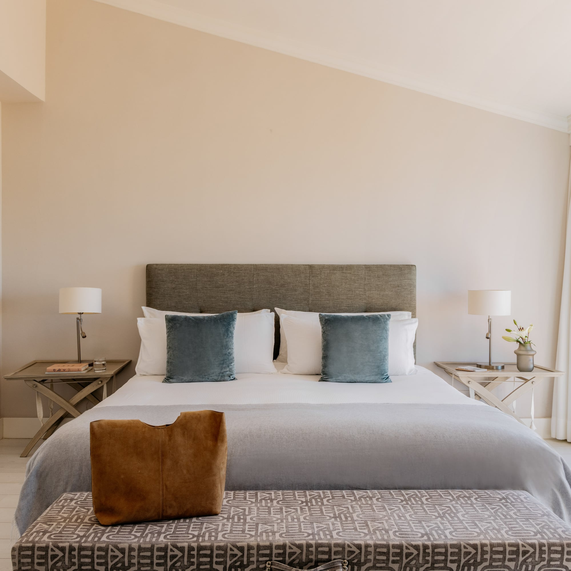 Elegant bedroom with king bed, ocean view balcony, and light decor.