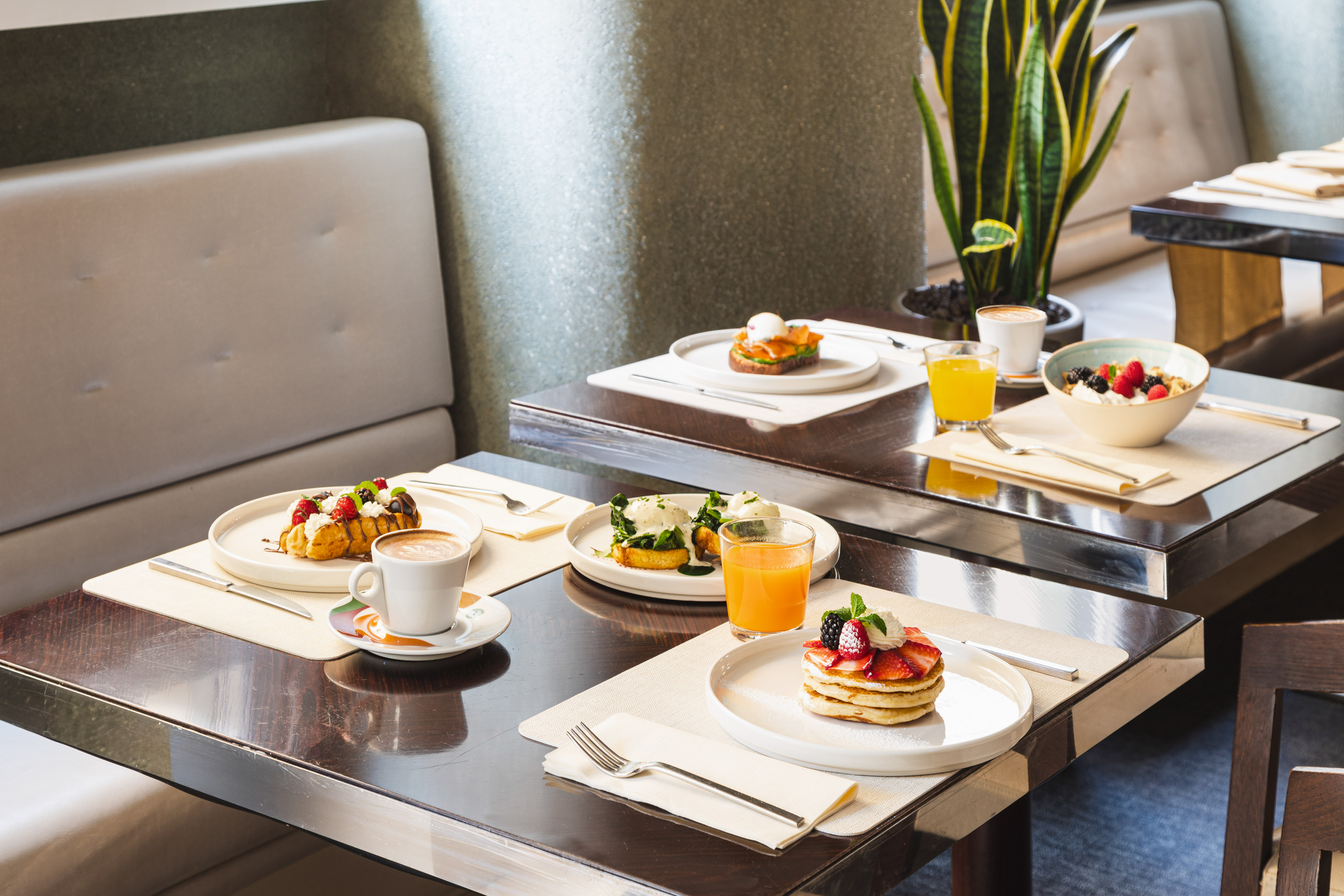 Restaurant breakfast tables: pancakes, waffles, eggs, coffee, orange juice.