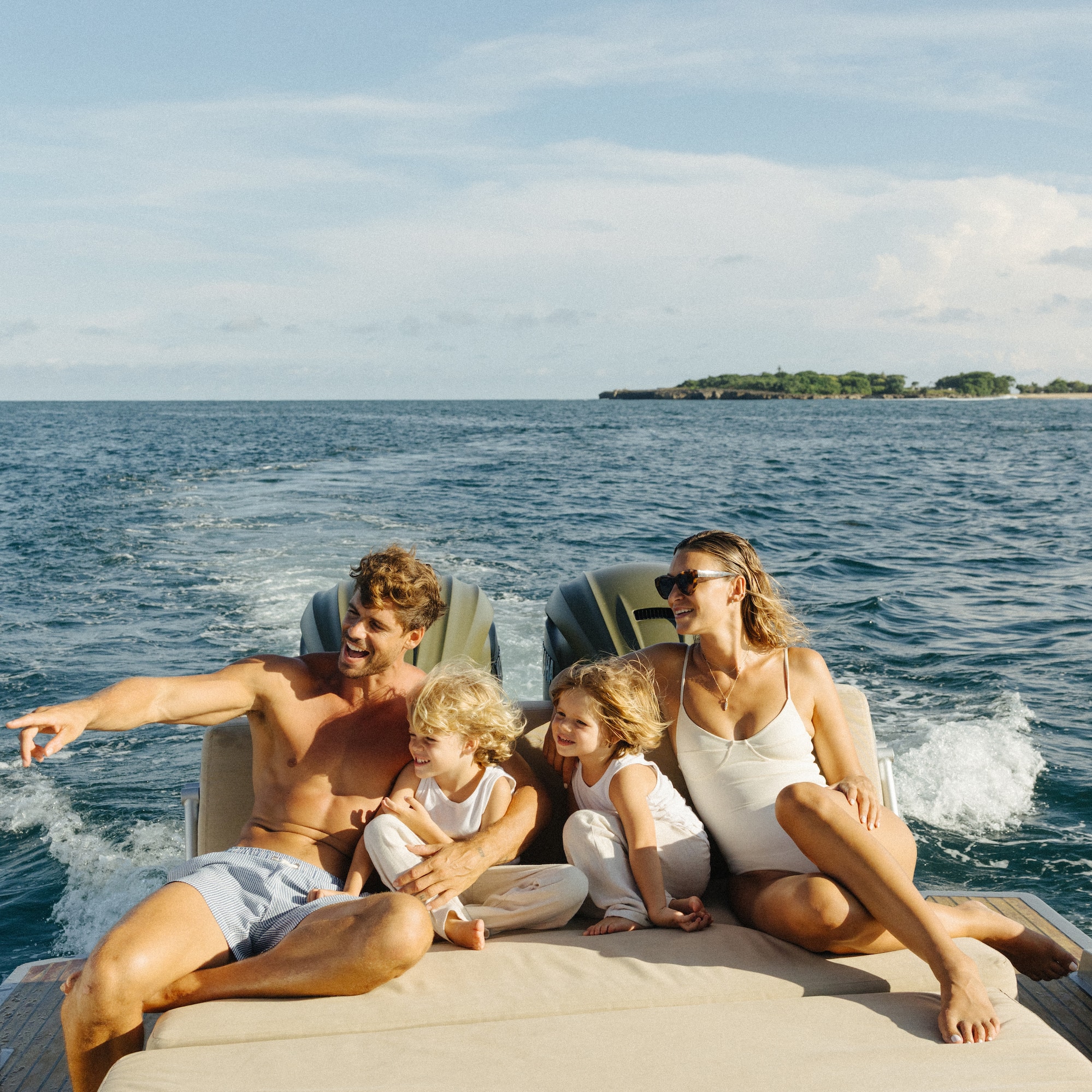 Family enjoying a sunny boat ride with kids on the open ocean.