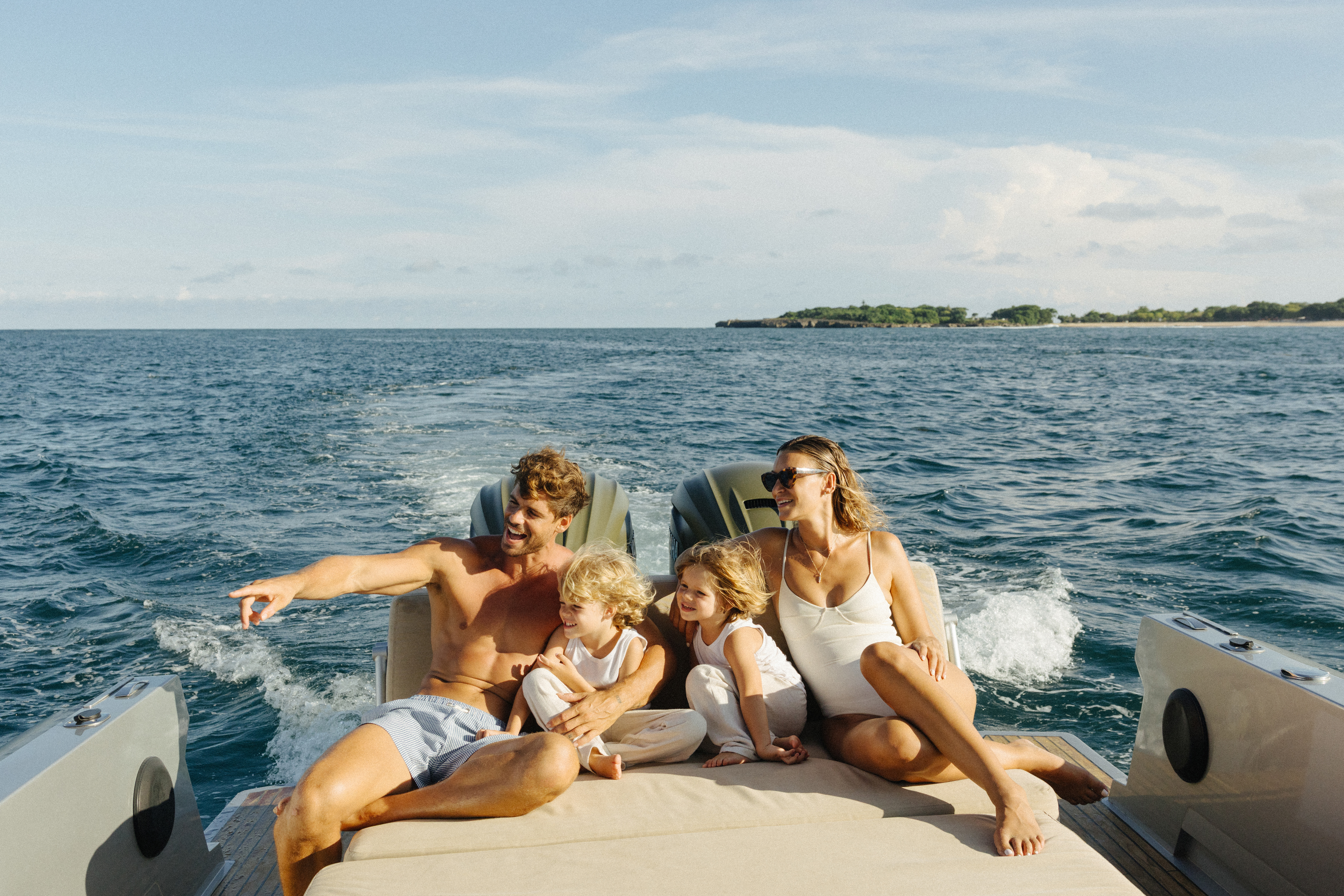 Family enjoying a sunny boat ride with kids on the open ocean.