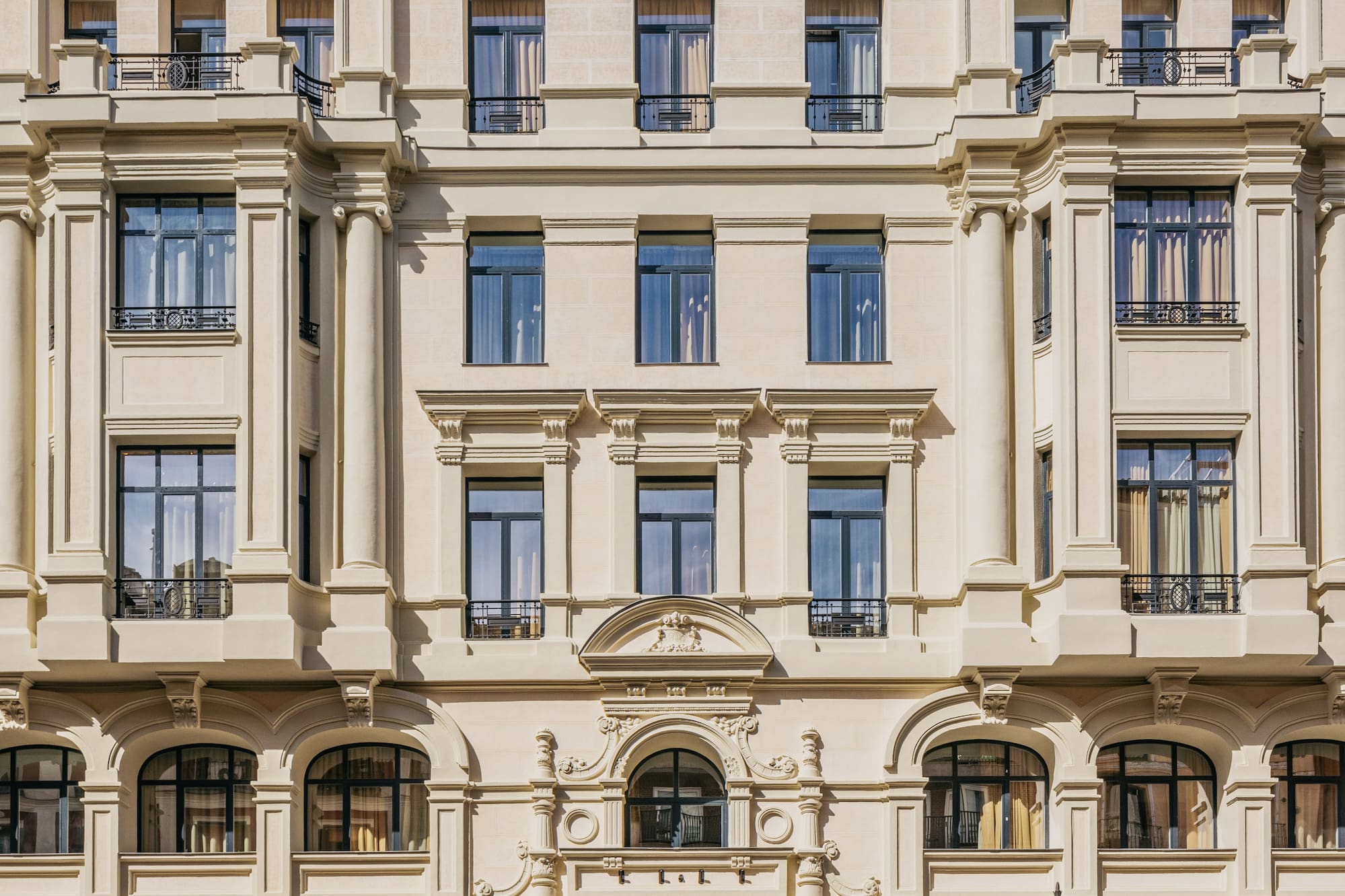 Ornate cream building facade with classical columns, arched windows, street entrance.